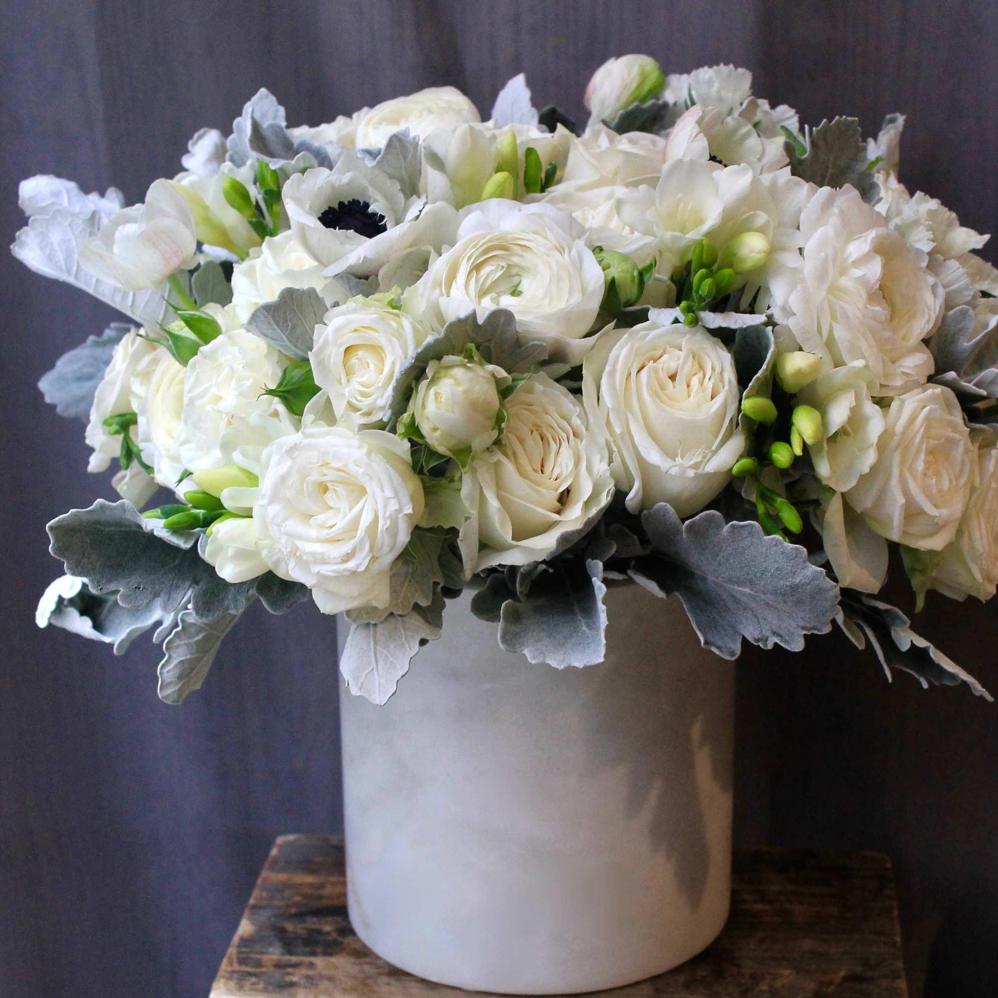 White rose arrangement in a tall white vase