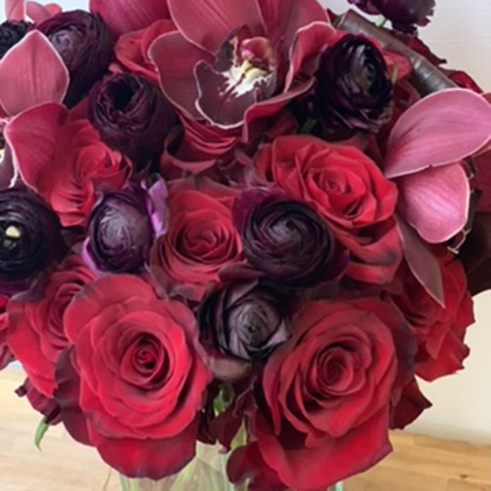 Bouquet of red roses and dark calla lilies in a clear glass vase