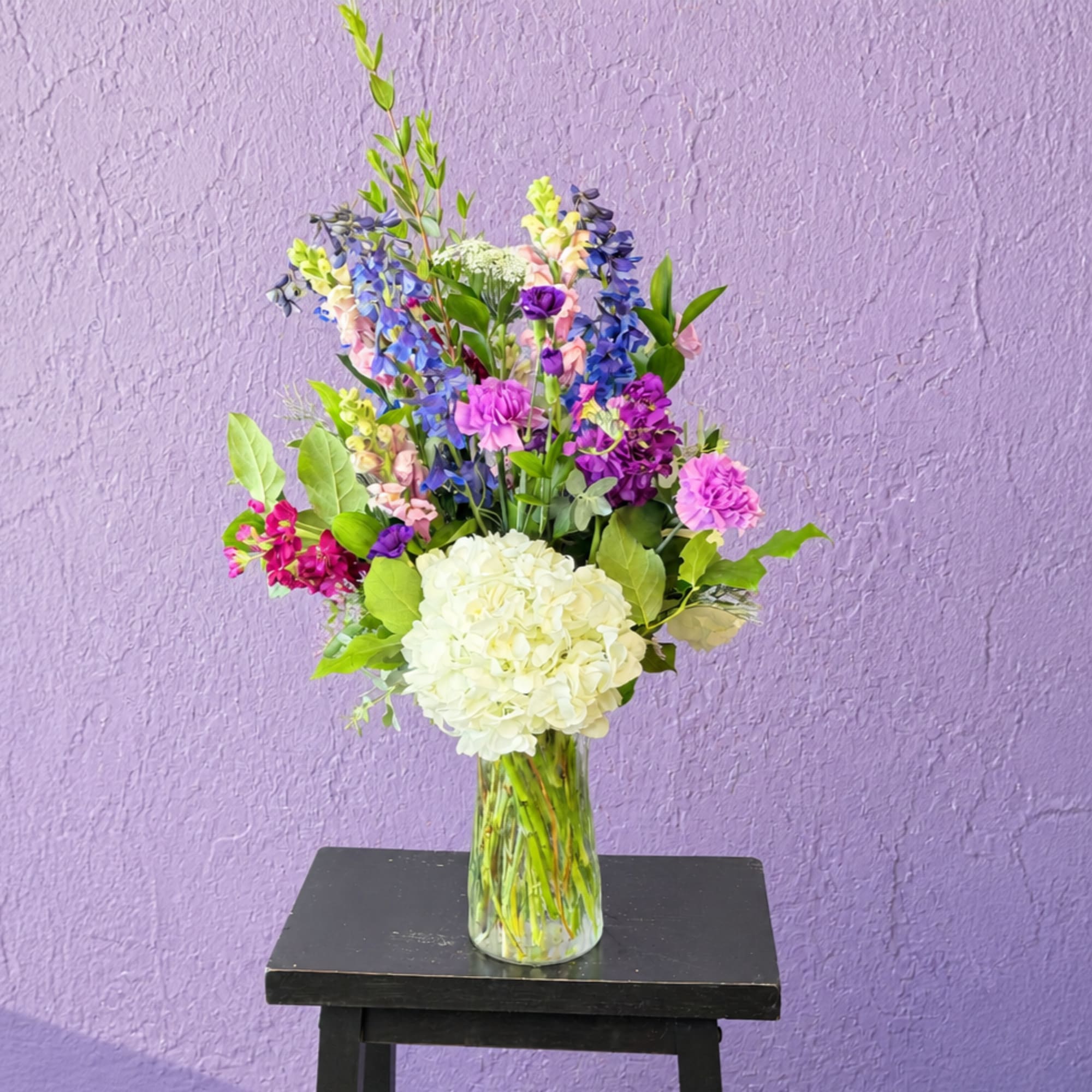 Mixed bouquet in a clear glass vase with white hydrangea and purple-blue flowers