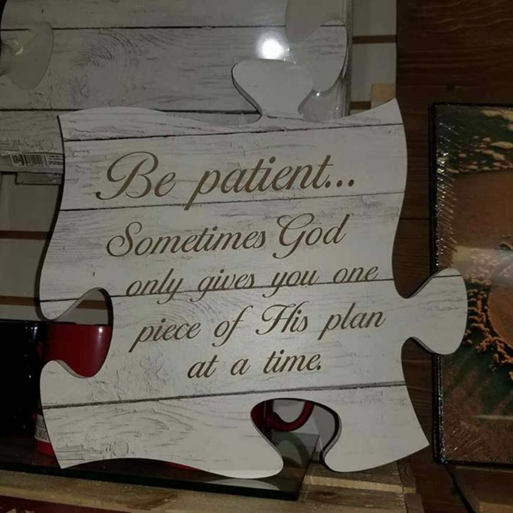 Puzzle-piece sign with a religious quote on a wood-look background
