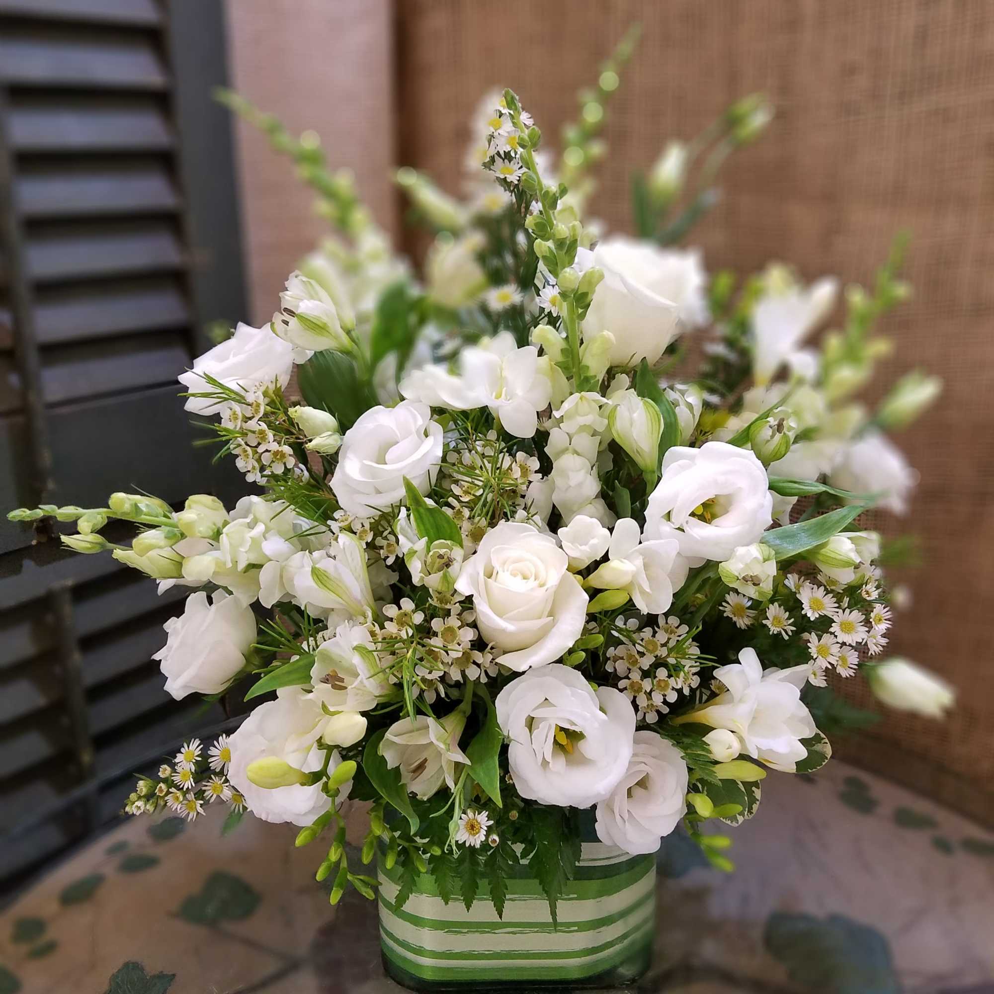 White floral arrangement in a striped green vase
