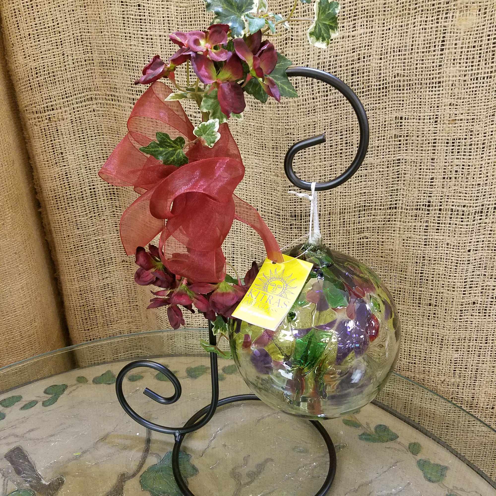 Decorative glass orb with purple flowers on a black metal stand