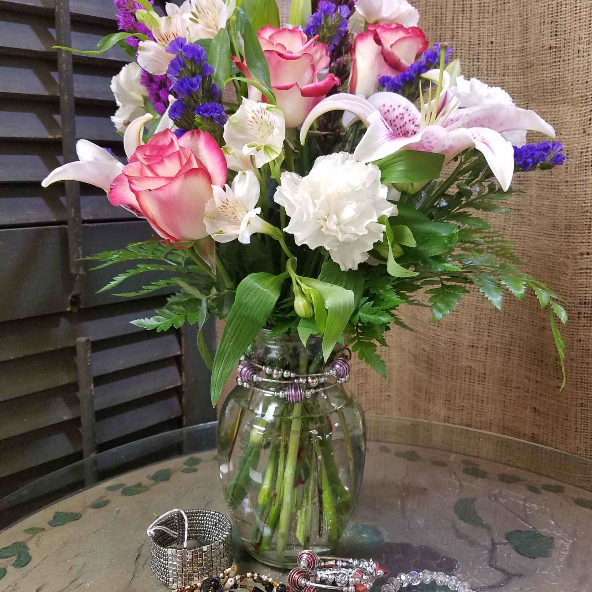 Pink and white roses with lilies in a glass vase