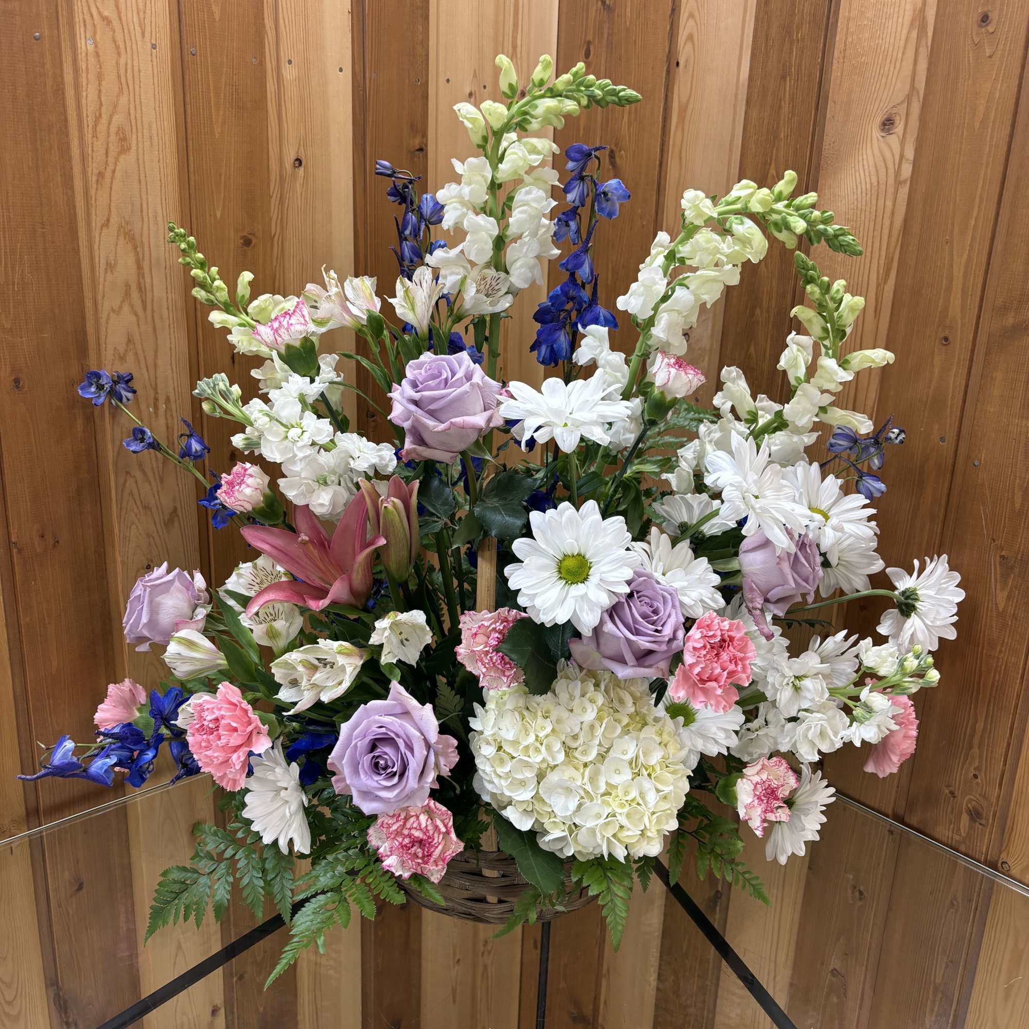 Mixed bouquet in a basket with lavender roses, white daisies, and blue flowers