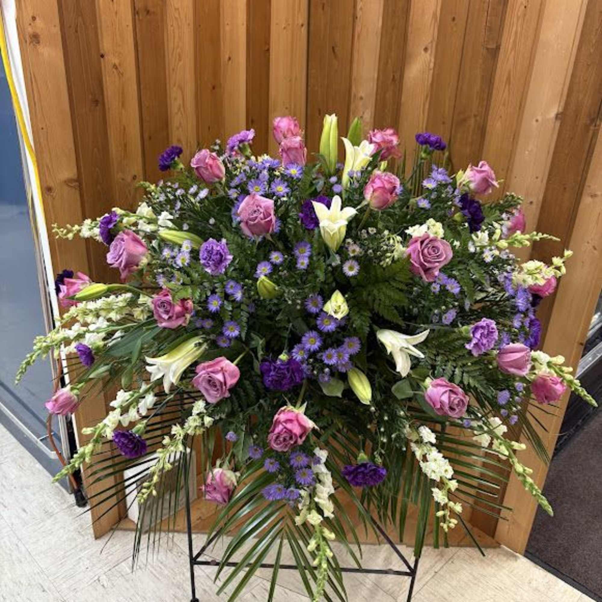 Large standing floral spray with pink roses, white lilies, and purple accents