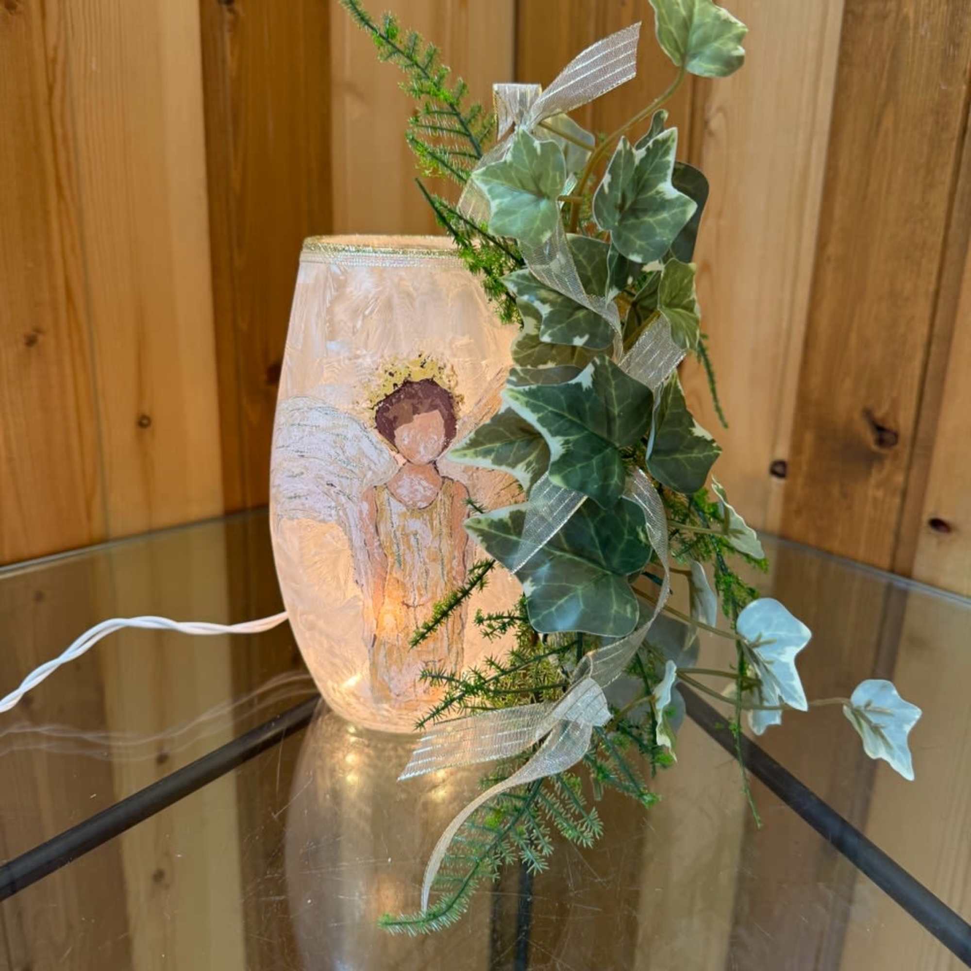 Lit glass candle holder with ivy and ribbon decoration