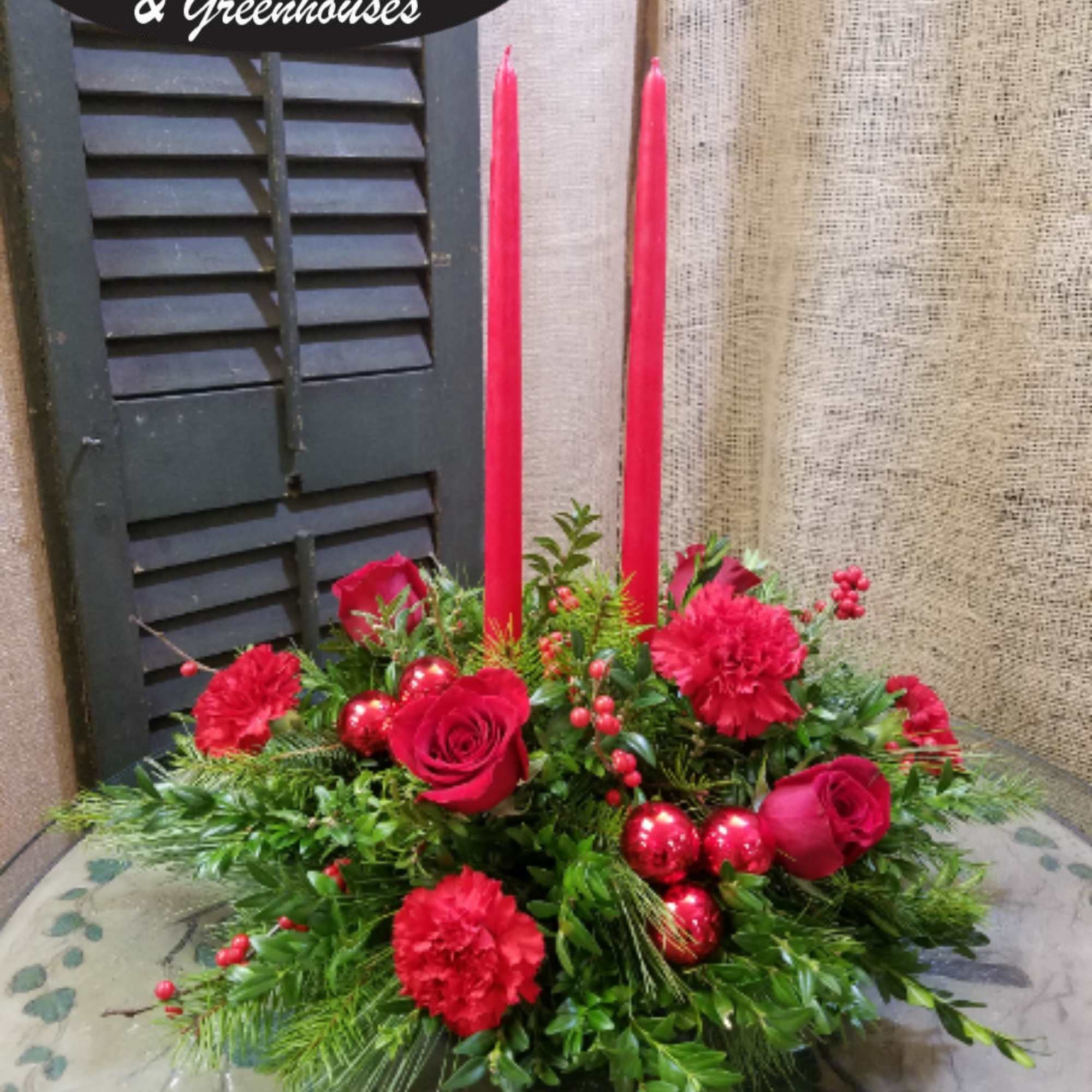 Red roses and carnations with tall red candles in a low arrangement