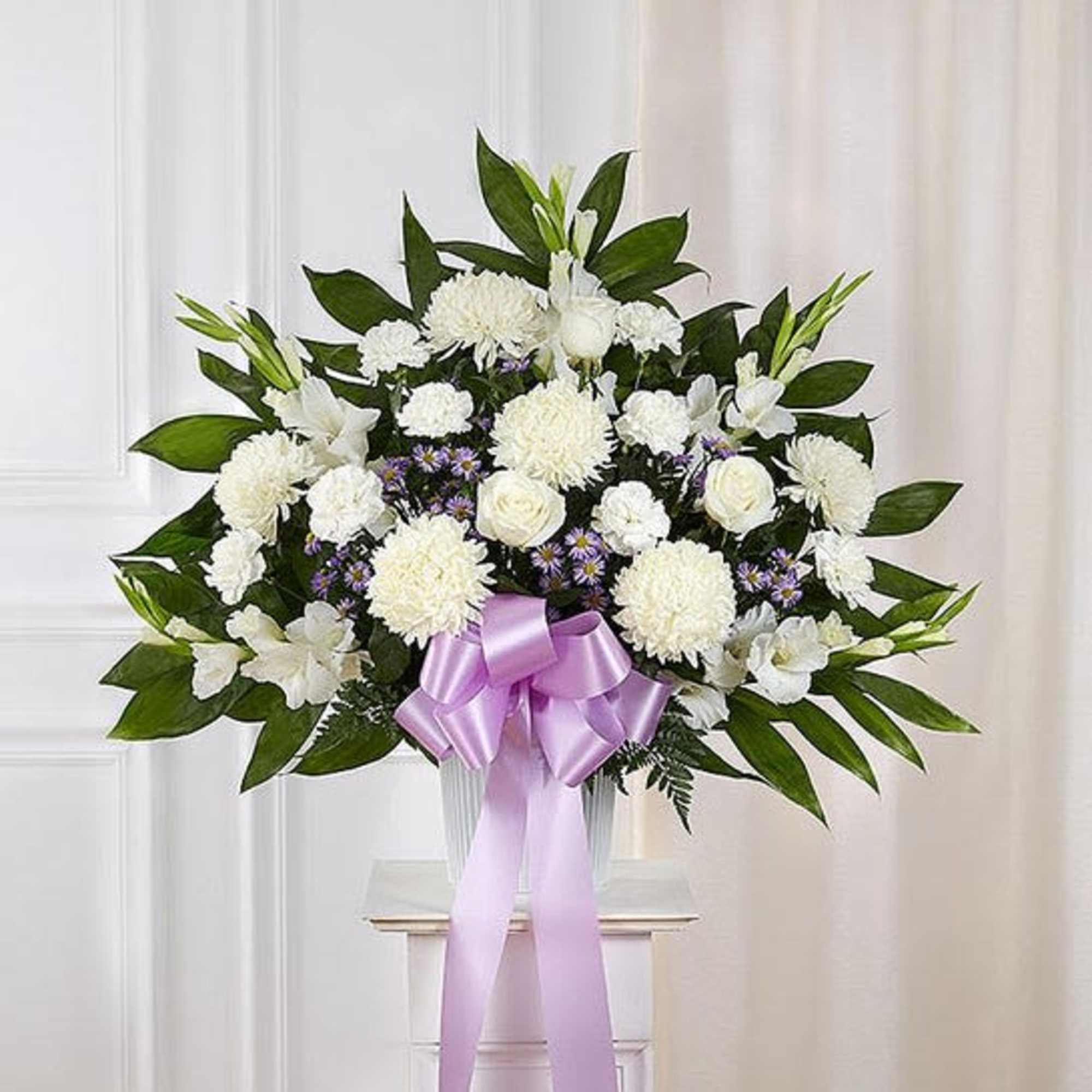 White floral arrangement with a lavender ribbon in a clear vase