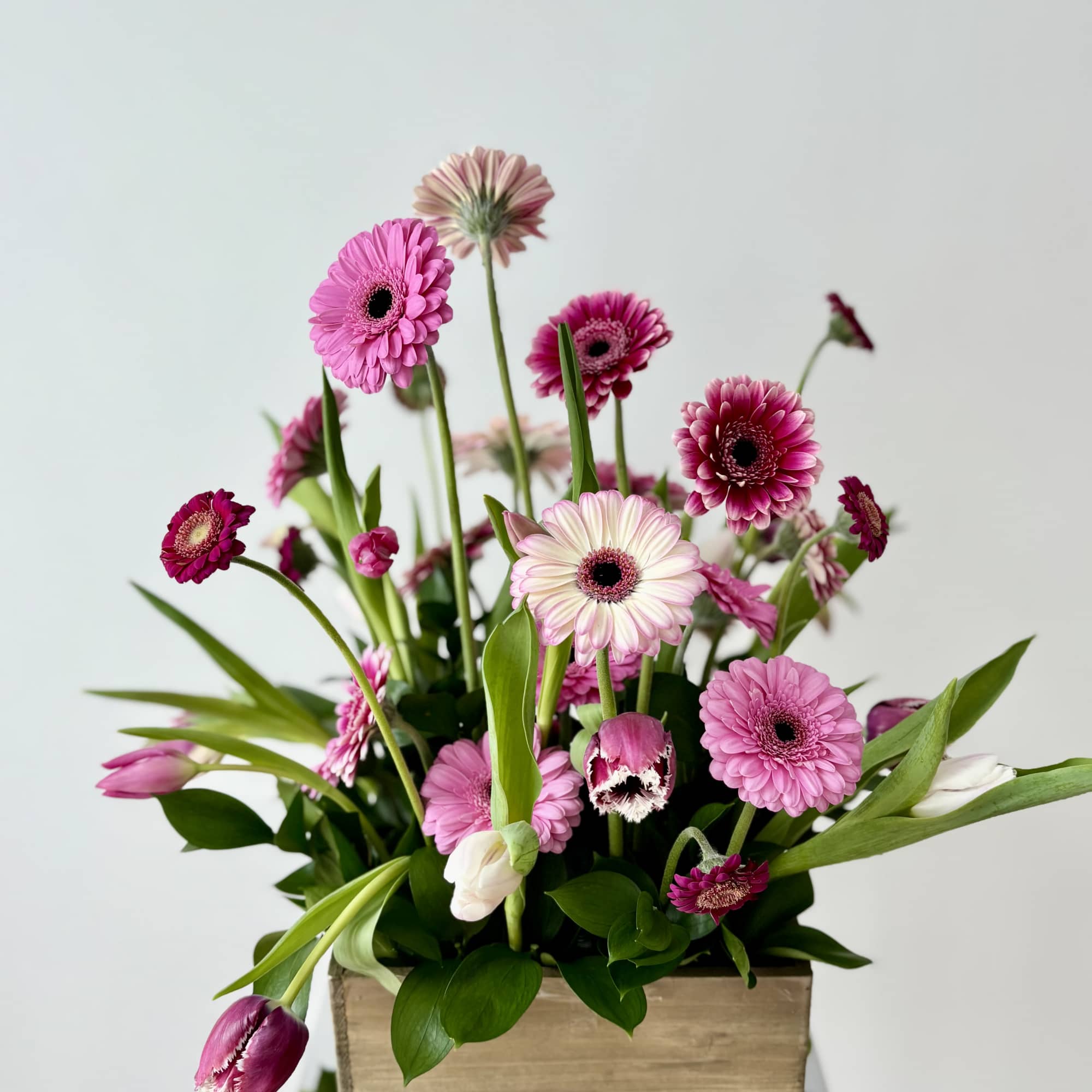 Pink gerbera daisies and tulips arranged in a wooden box, photo 2 of 2