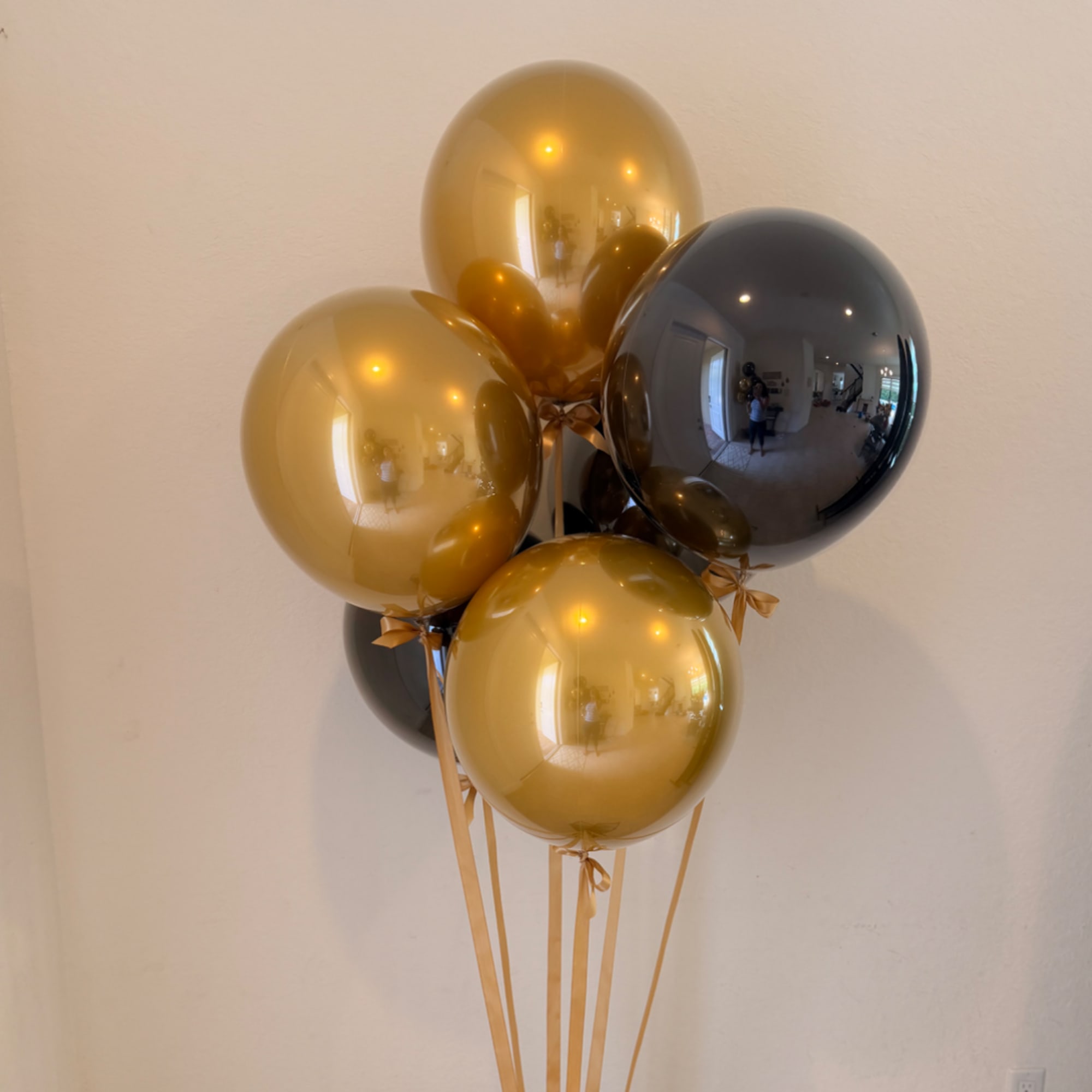 Cluster of gold and black balloons tied with ribbons