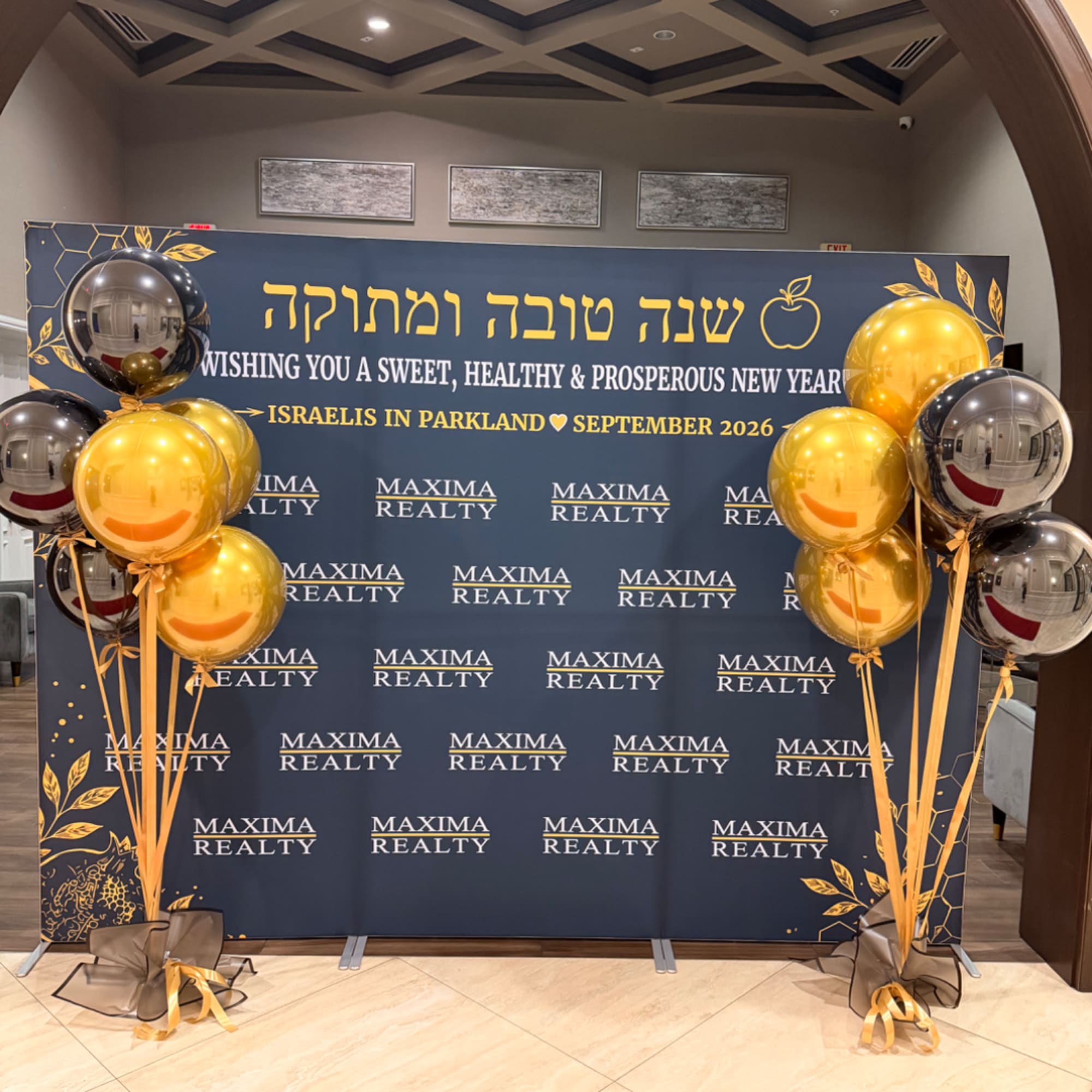Gold and silver balloons flank a New Year event backdrop