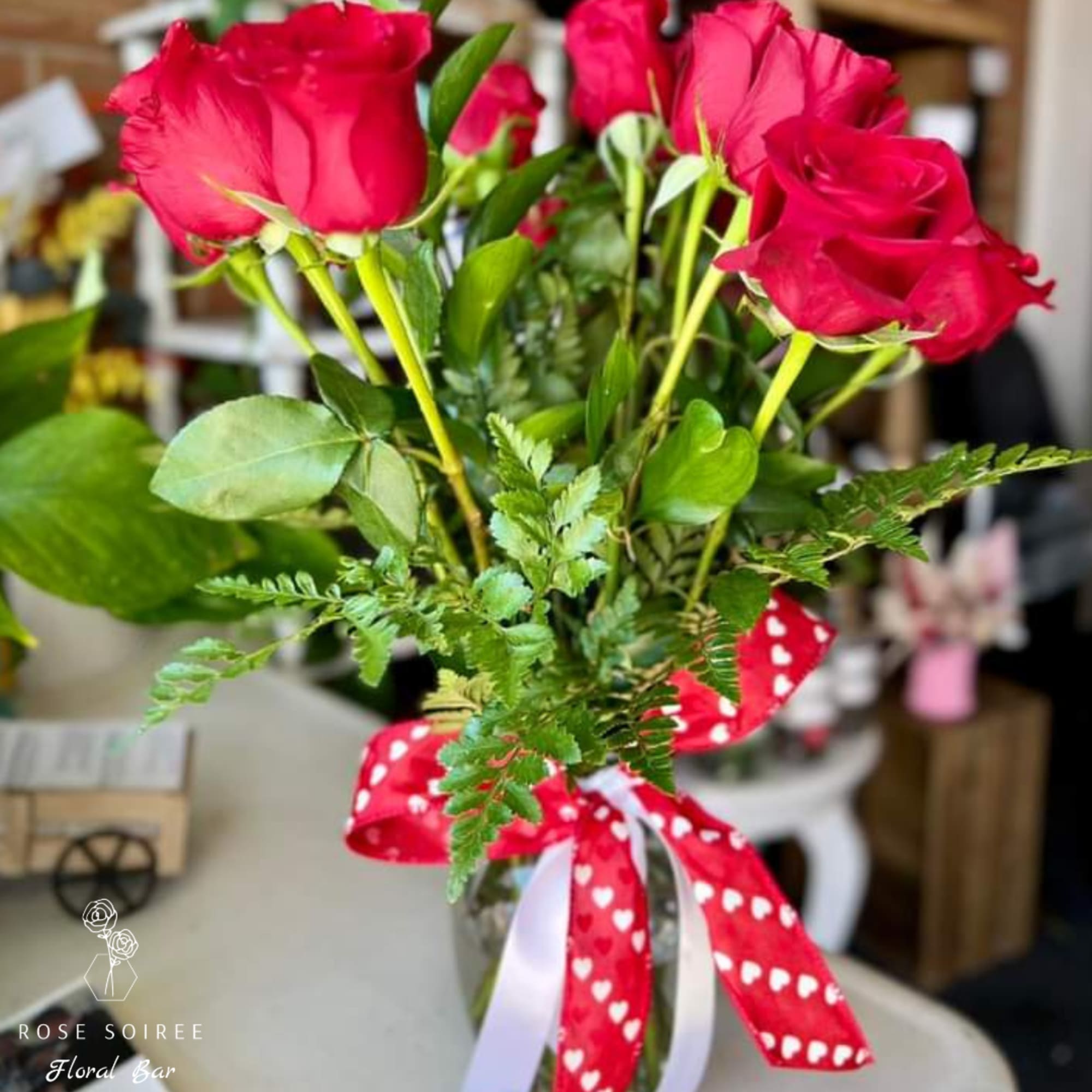 Bouquet of red roses with a heart-patterned ribbon in a glass vase