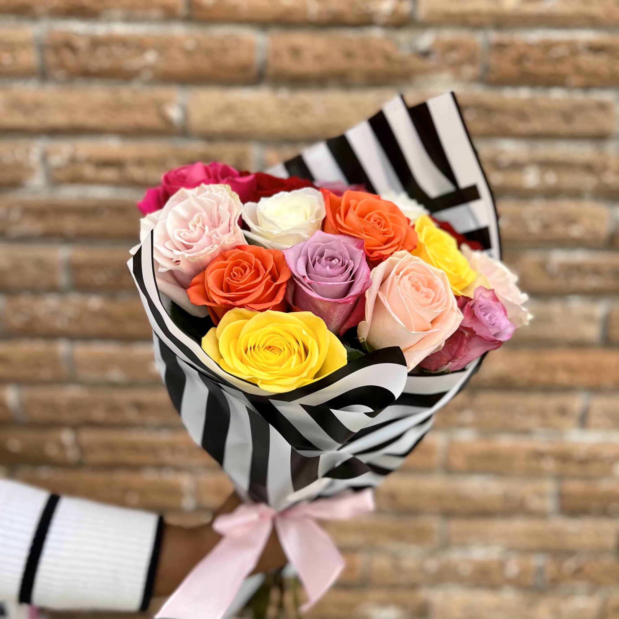 Bouquet of multicolored roses wrapped in black-and-white striped paper