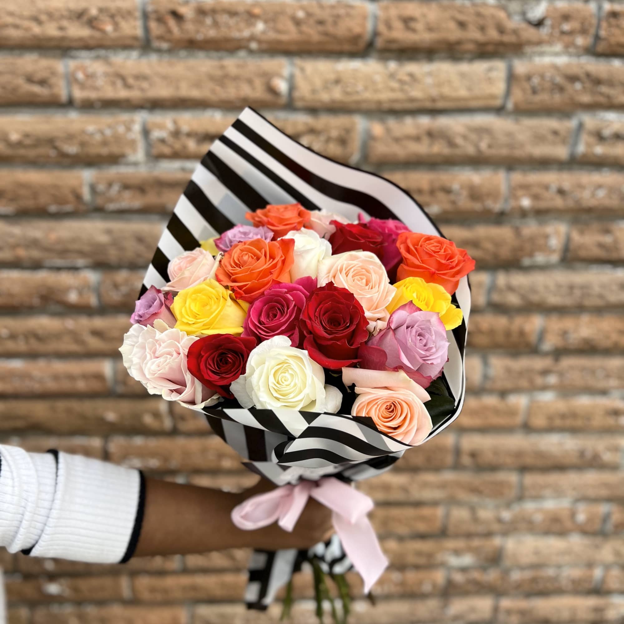 Bouquet of multicolored roses wrapped in black-and-white striped paper