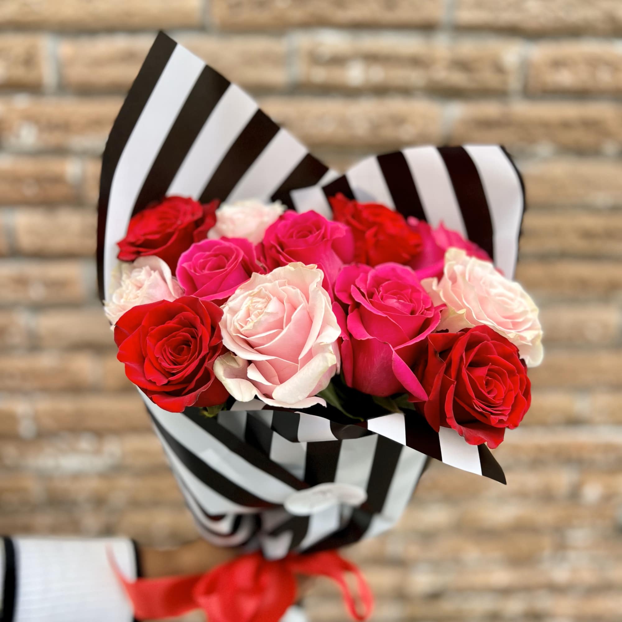 Bouquet of red, pink, and white roses wrapped in black-and-white striped paper