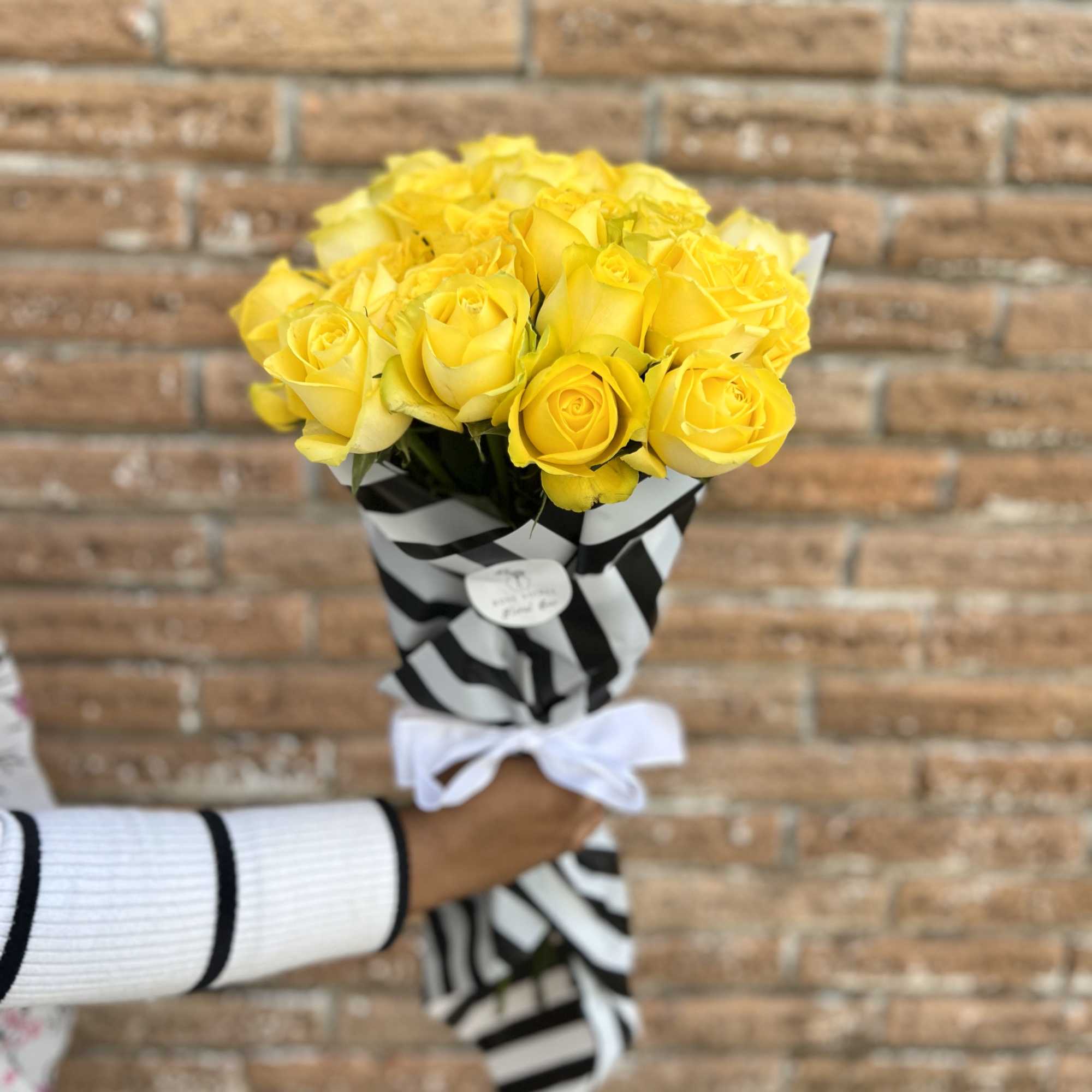 Bouquet of yellow roses wrapped in black-and-white striped paper