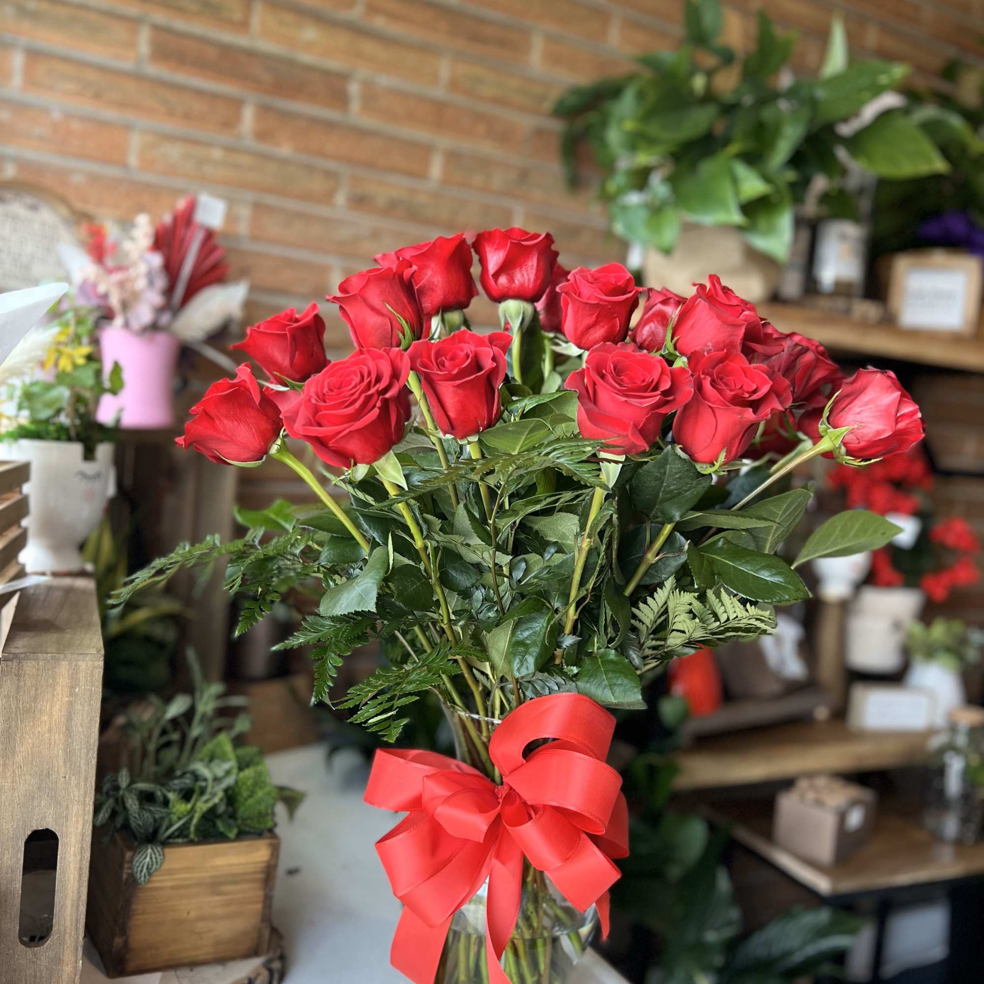 Bouquet of red roses in a clear glass vase with a red ribbon