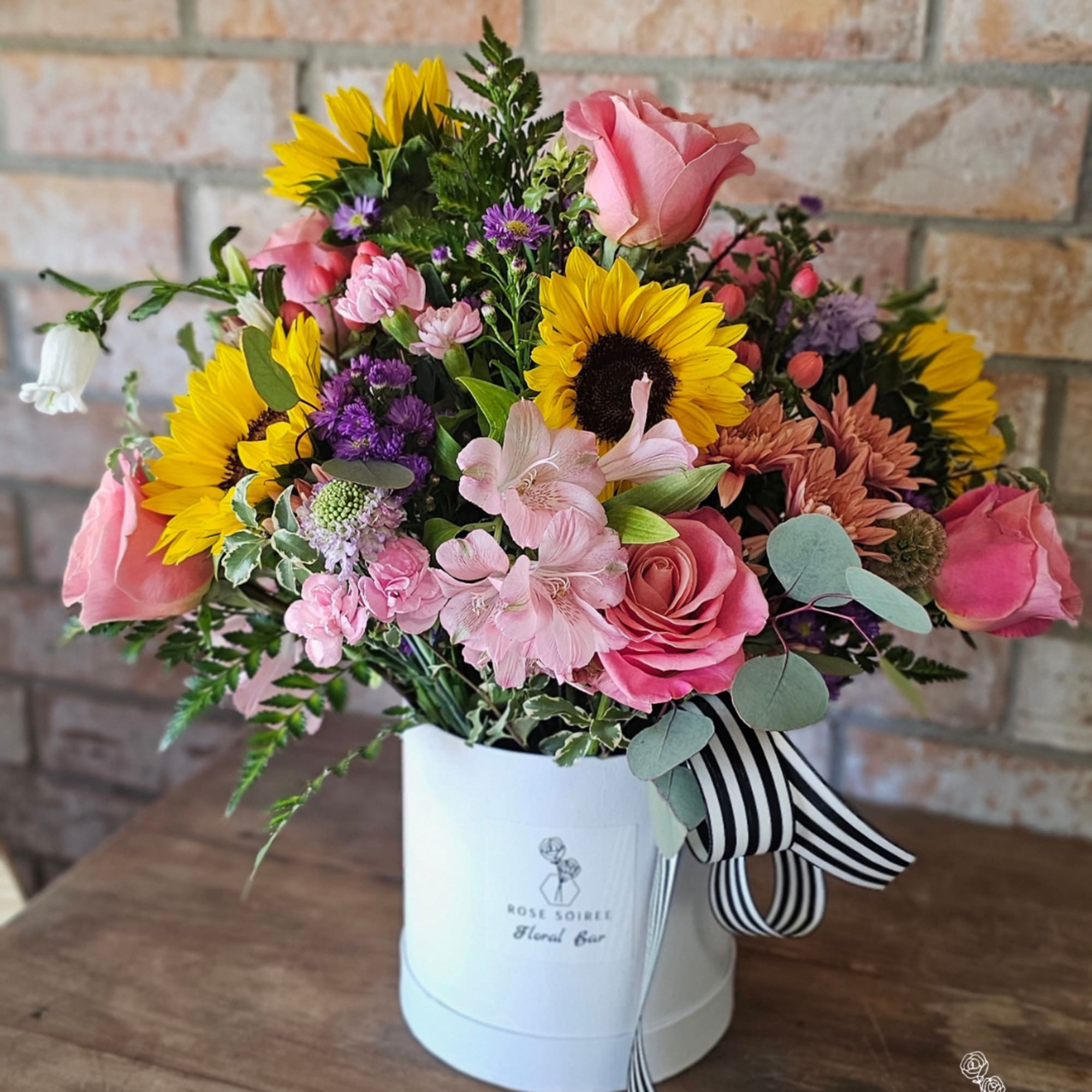 Mixed bouquet of sunflowers and pink roses in a white hat box with striped ribbon
