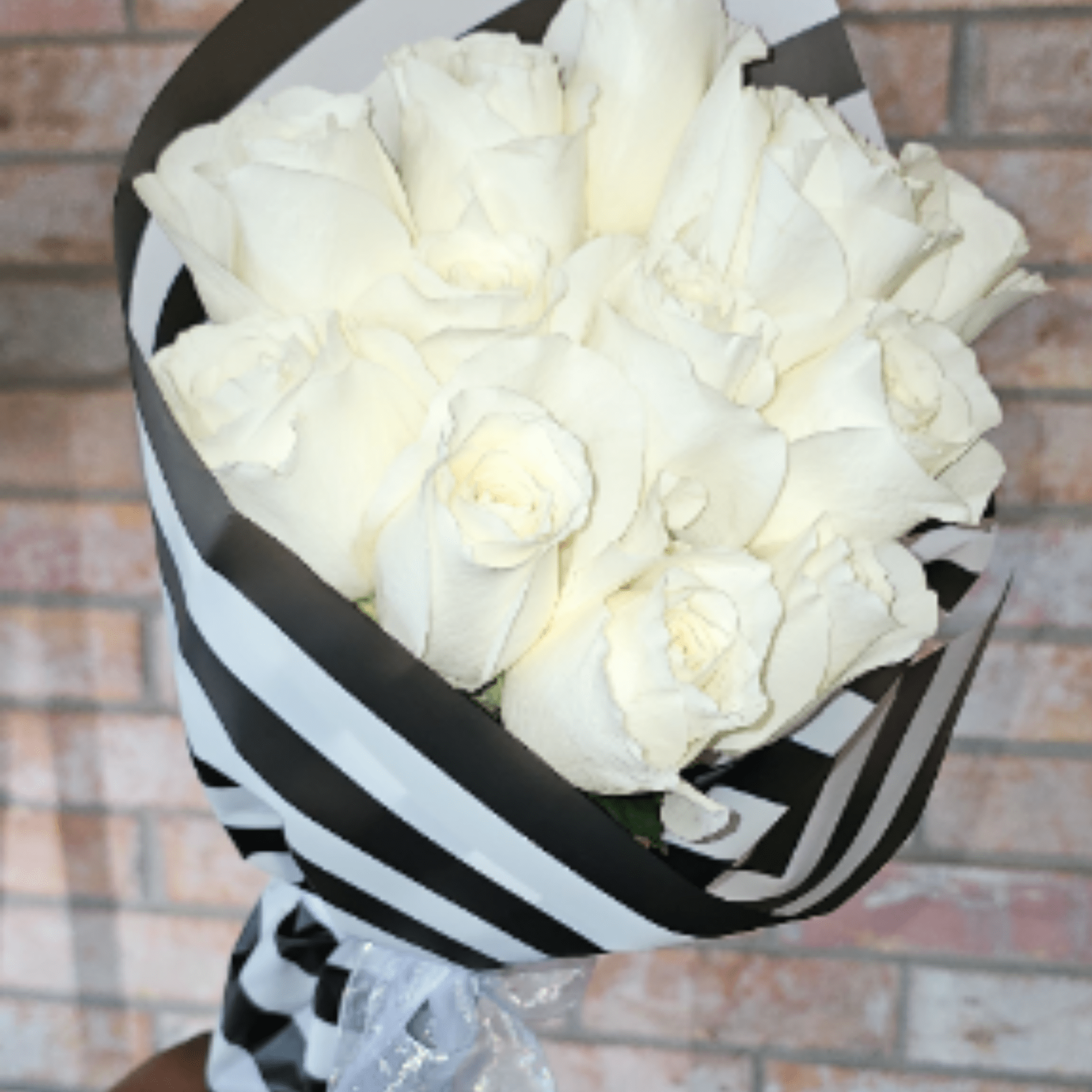 A timeless bouquet of premium ivory roses wrapped in our signature black-and-white
