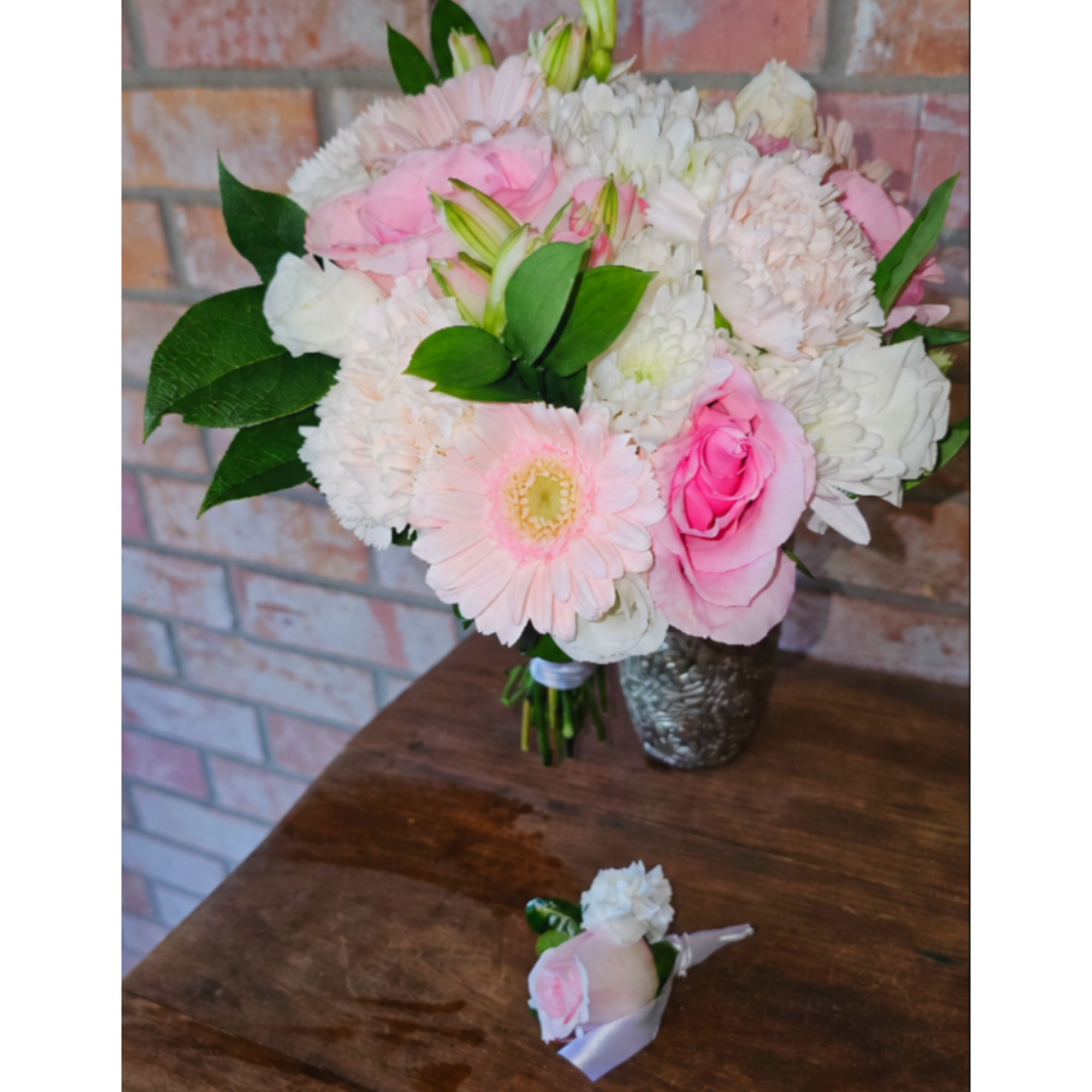 Pink and white bouquet in a silver vase with a matching boutonniere on a table
