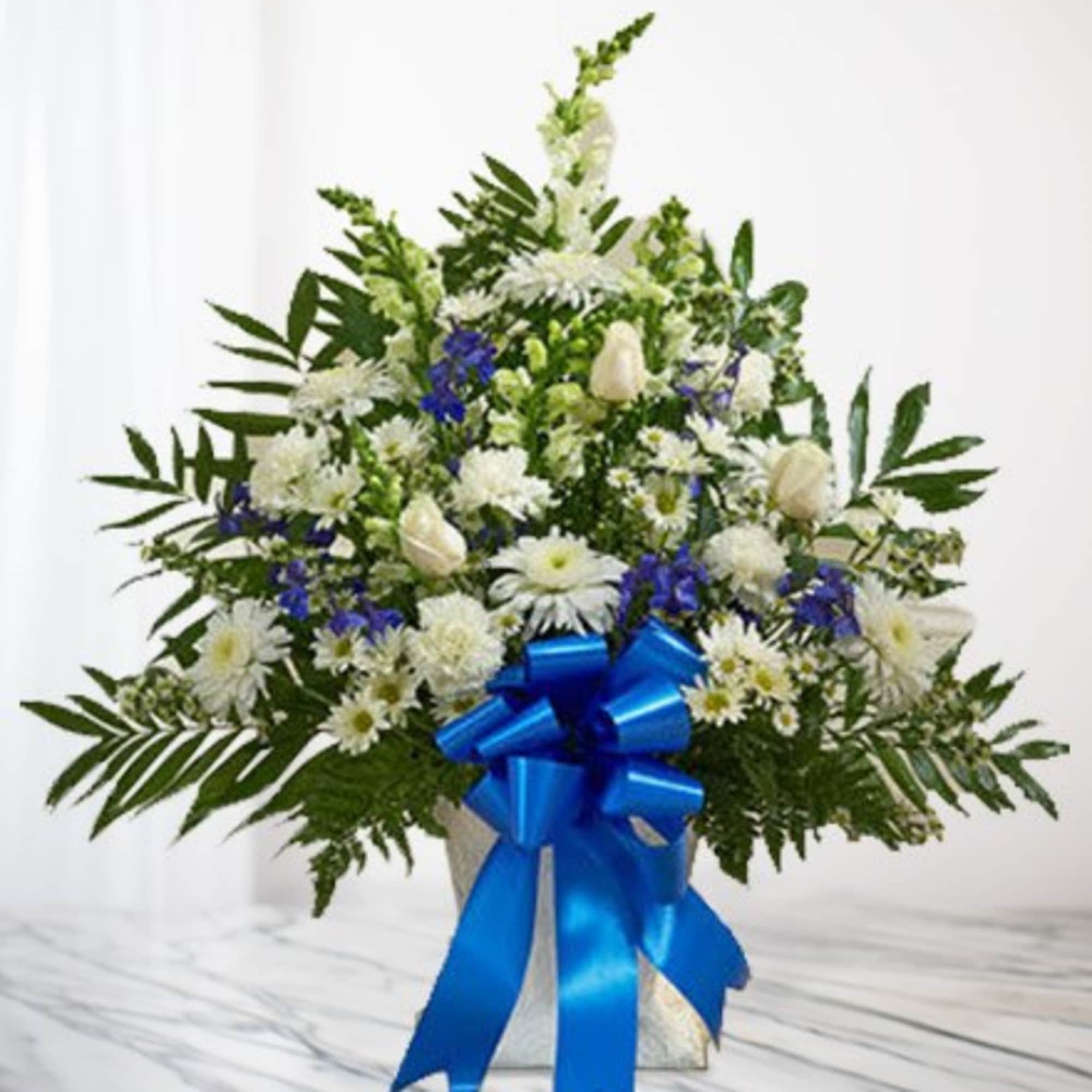 White and blue floral arrangement in a vase with a large blue ribbon