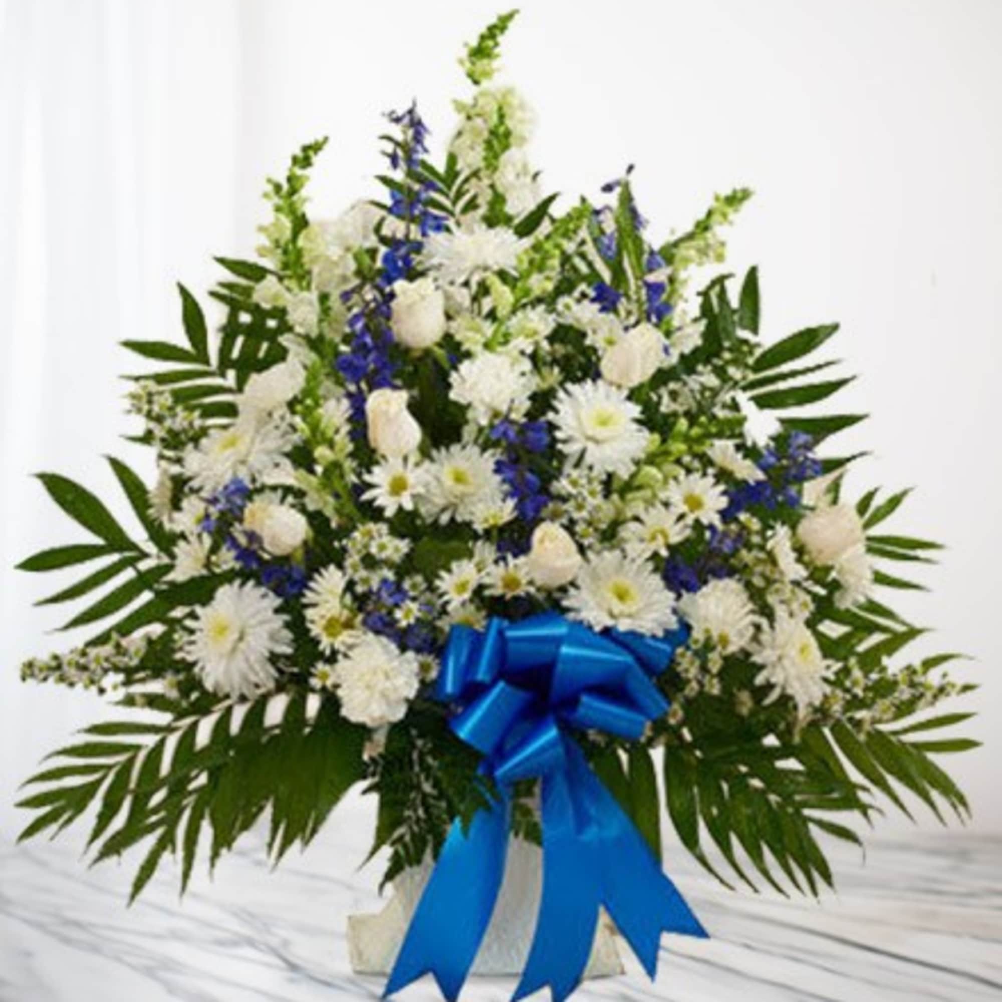 White and blue floral spray with a blue ribbon on a stand