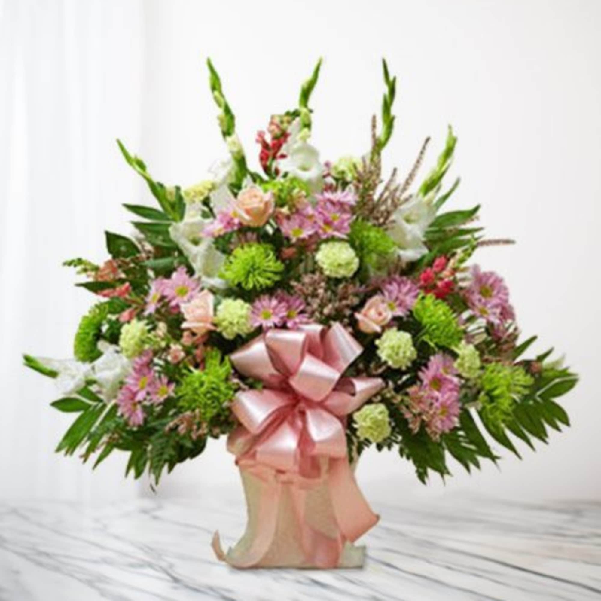 Pink and white floral arrangement with a large pink ribbon in a vase