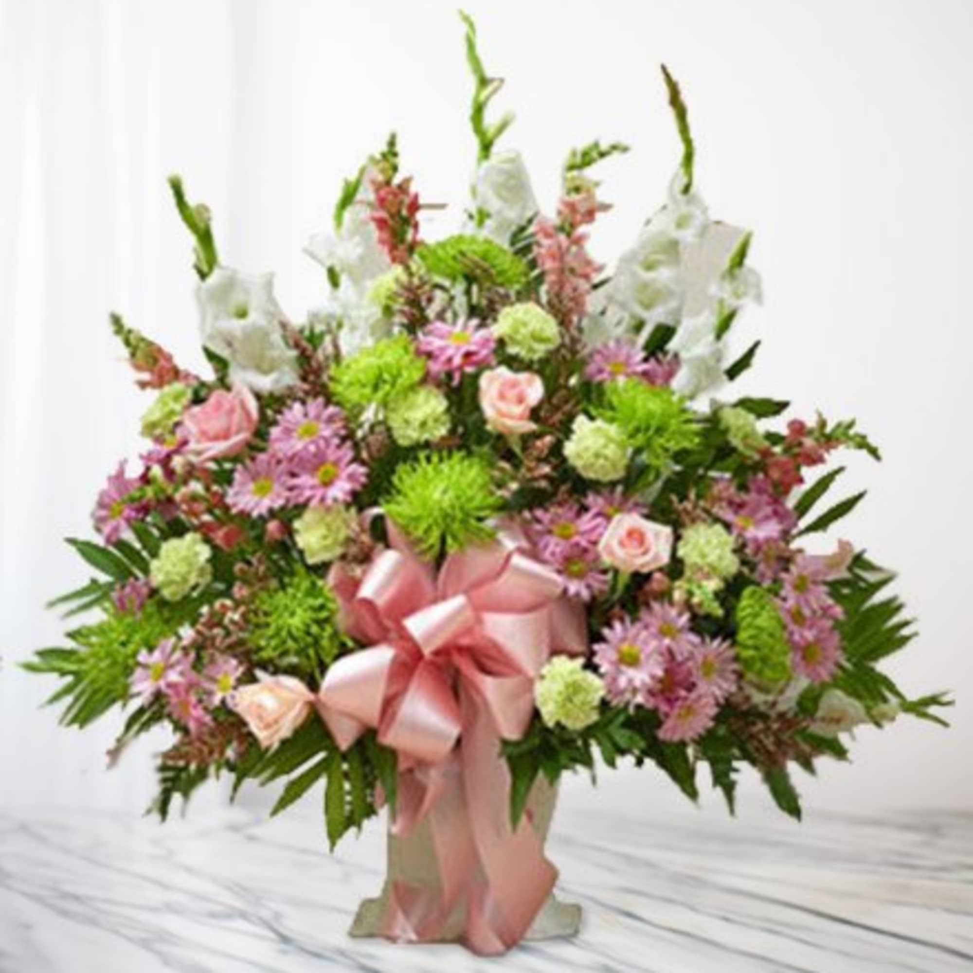 Pink and green floral arrangement with white blooms and a pink ribbon bow