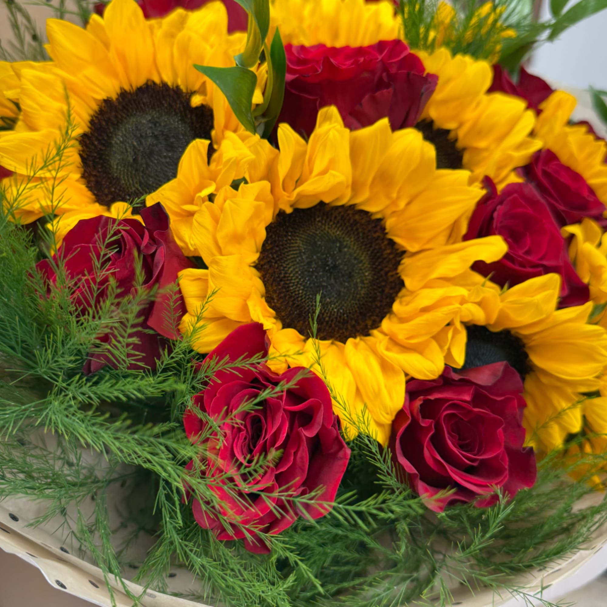 Bouquet of yellow sunflowers and red roses with greenery