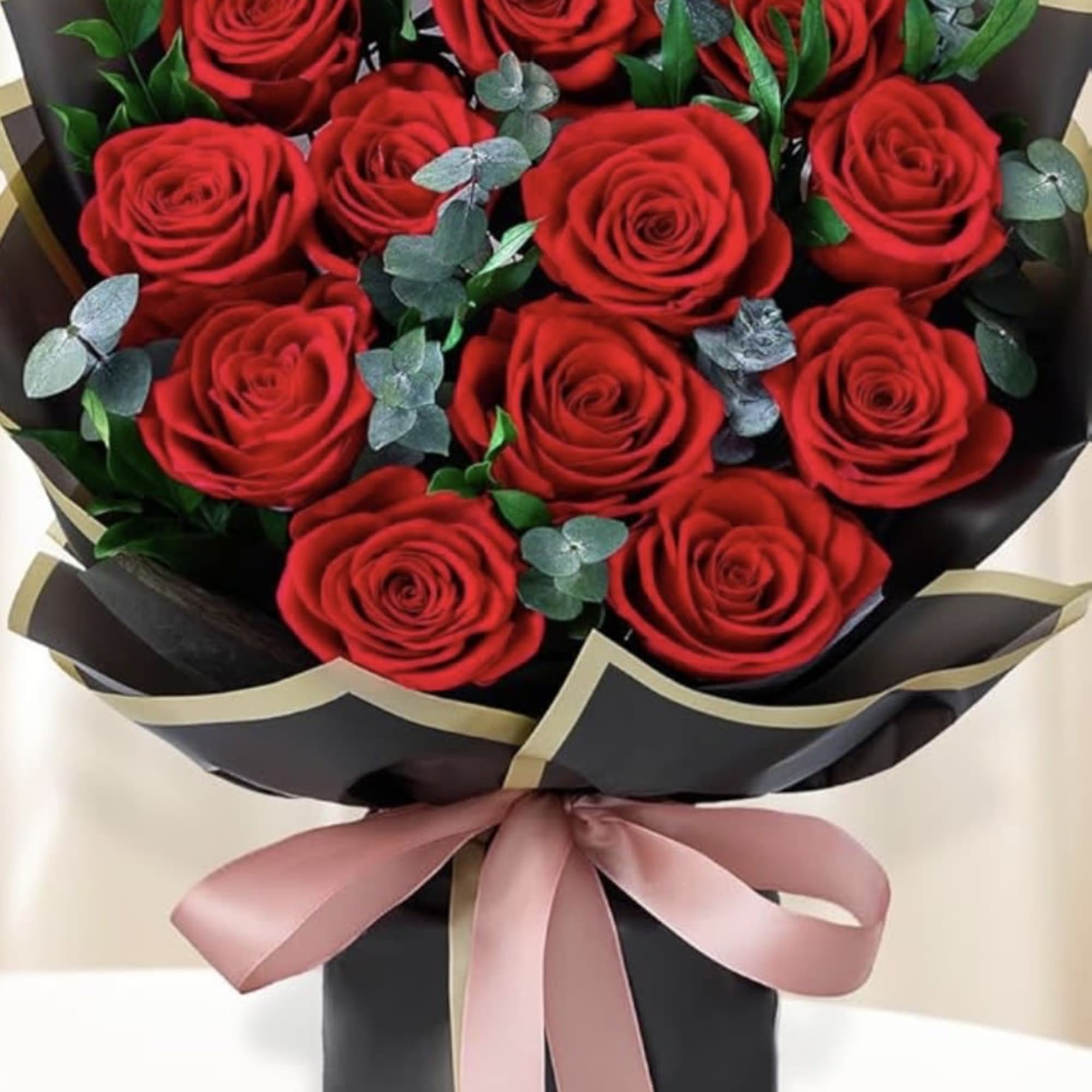 Bouquet of red roses wrapped in black paper with a pink ribbon