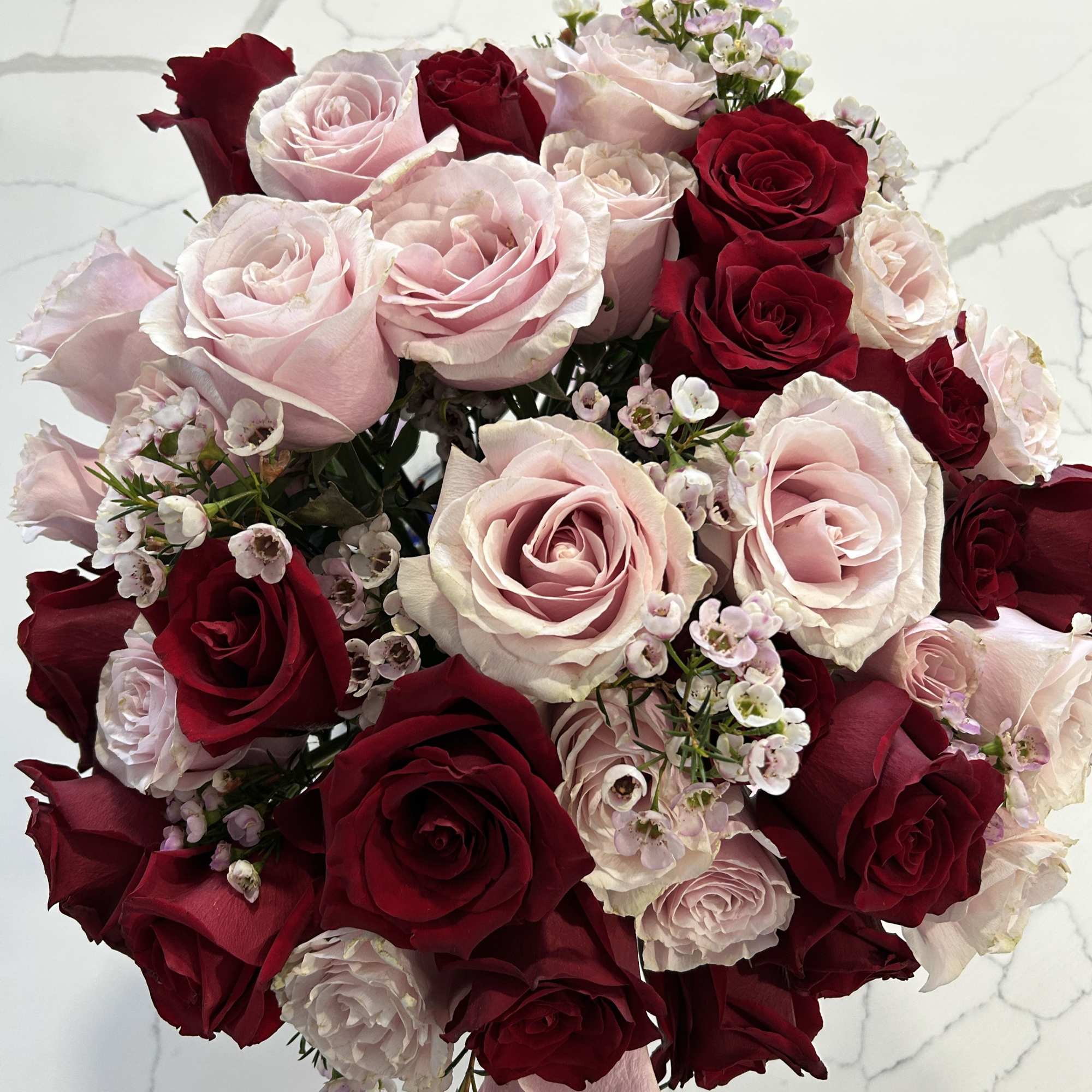 Bouquet of red and pale pink roses with small white filler flowers