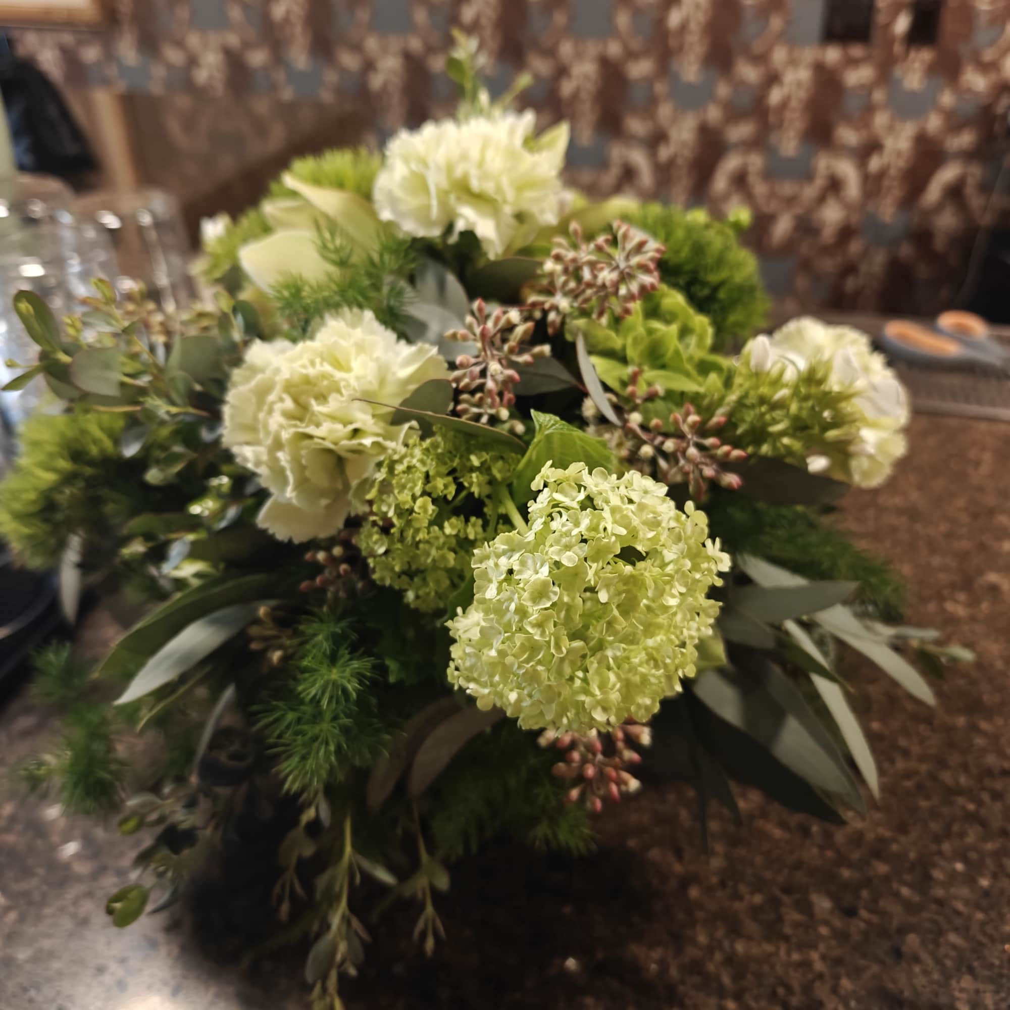 Shades of green flowers and foliage in a round centerpiece for the