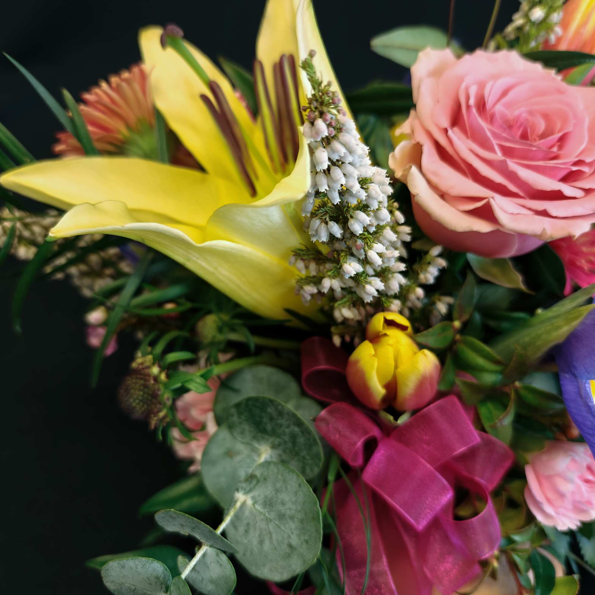 Bouquet with a pink rose, yellow lily, and tulips tied with a magenta ribbon
