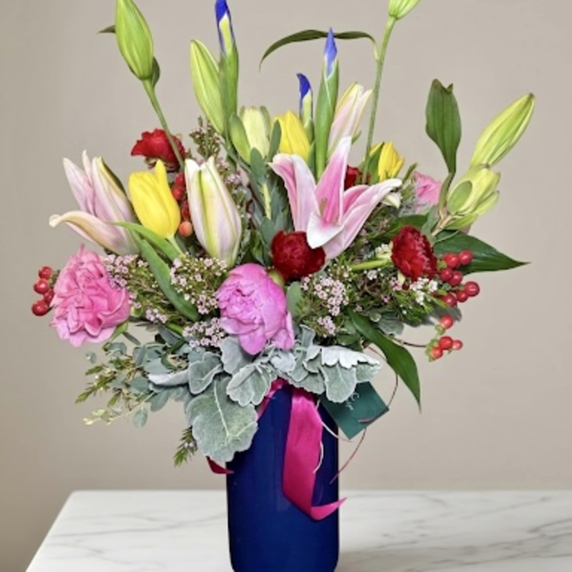 Colorful bouquet of lilies, tulips, and carnations in a blue vase