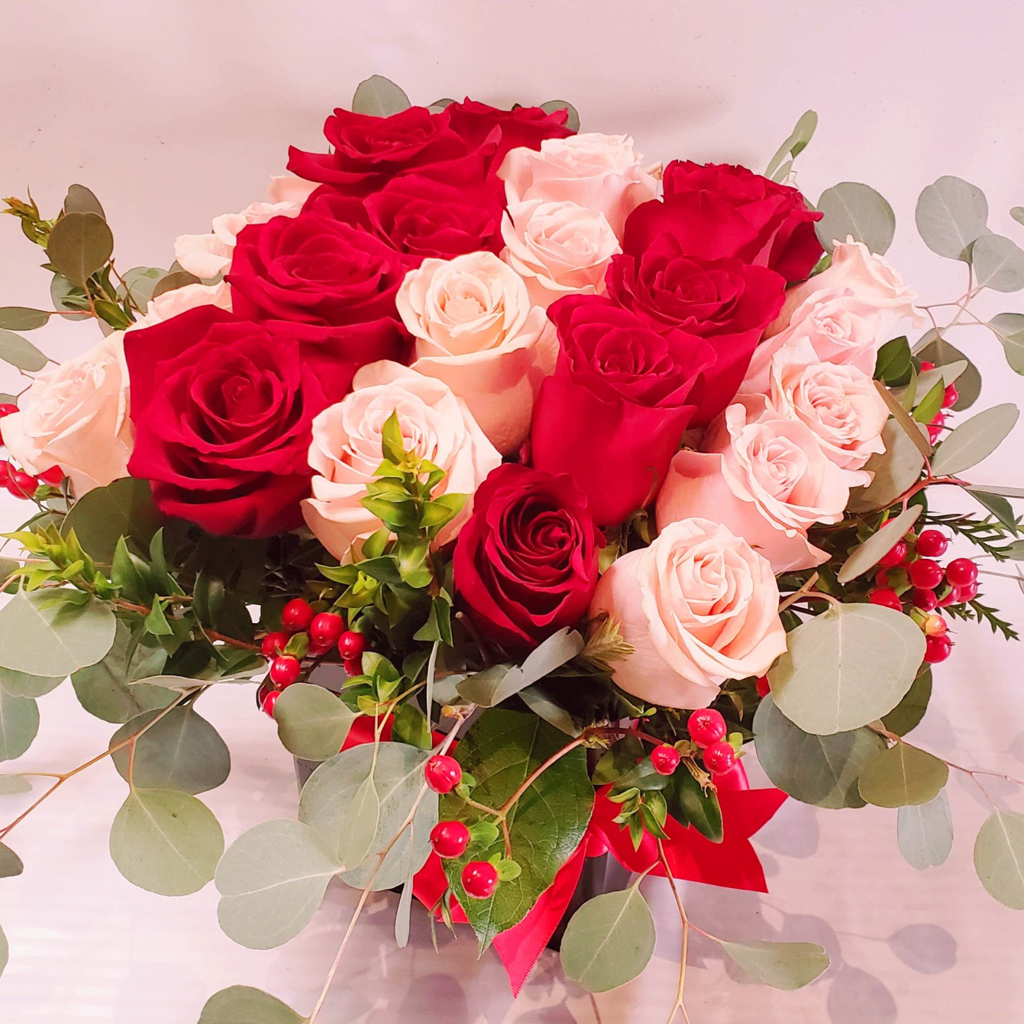 Bouquet of red and blush roses with eucalyptus and red berries