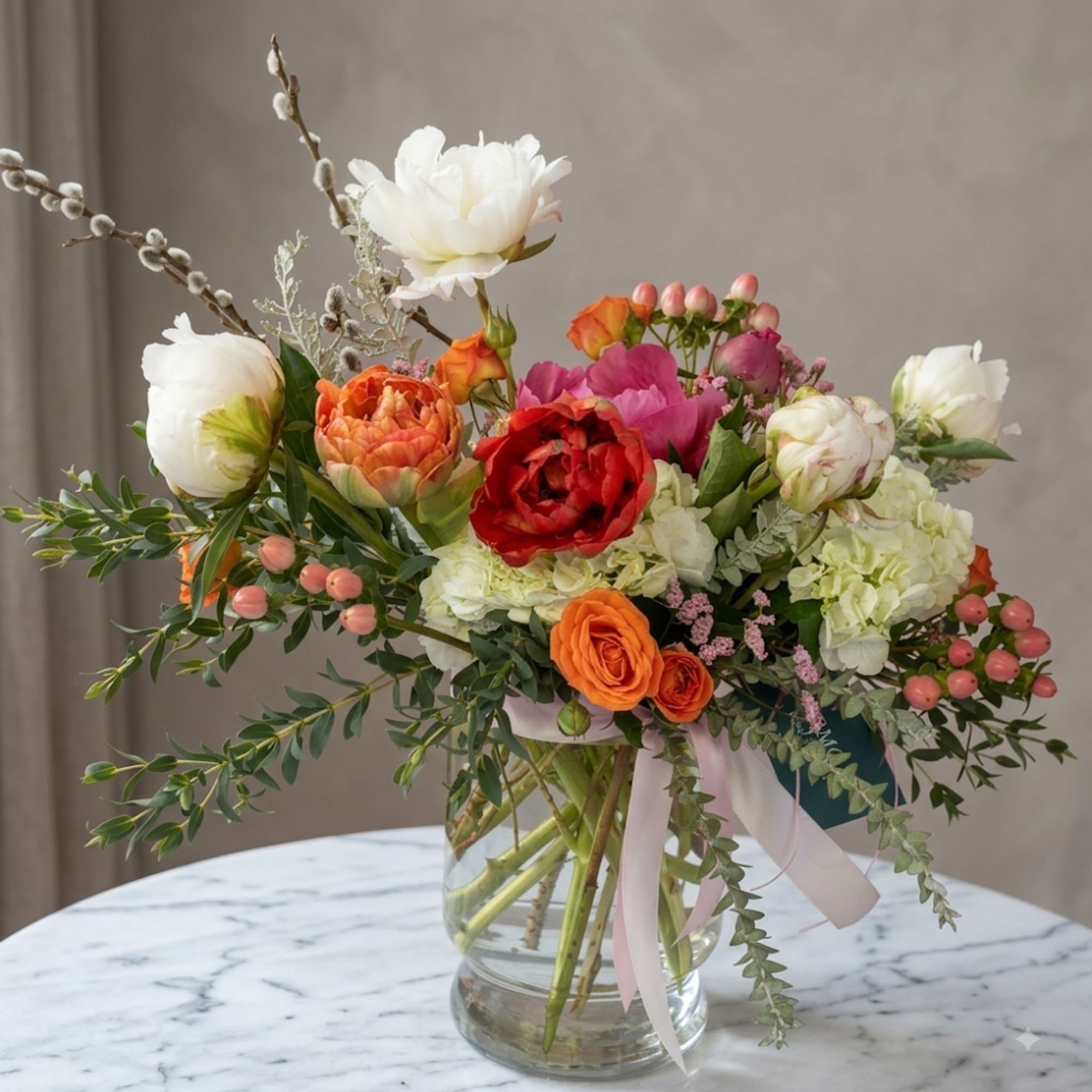Mixed bouquet of white, orange, red, and pink flowers in a glass vase