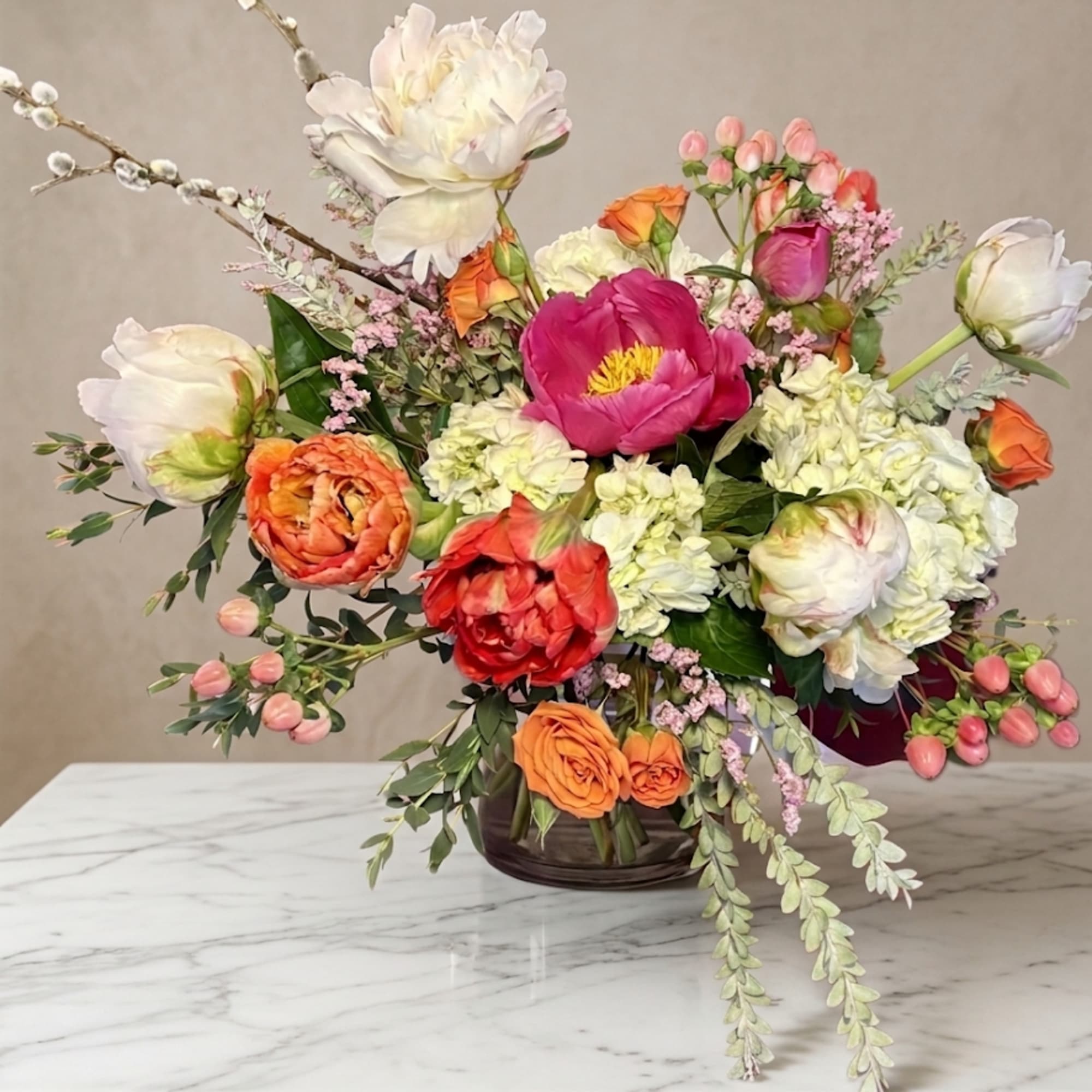 Mixed bouquet of pink, orange, white, and red flowers in a glass vase