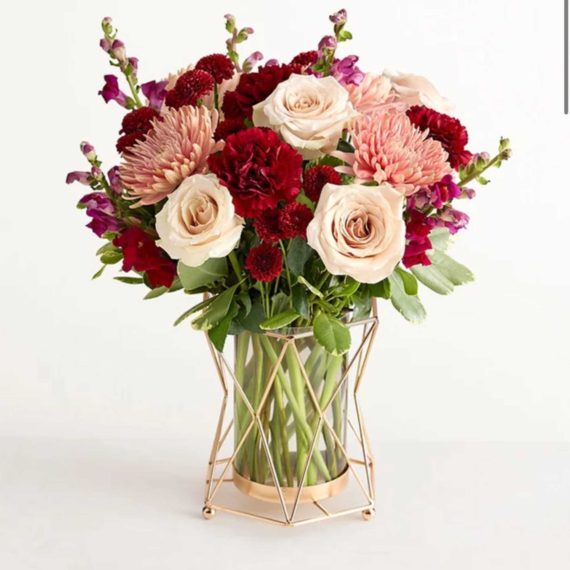 Bouquet of cream roses, pink mums, and red carnations in a glass vase