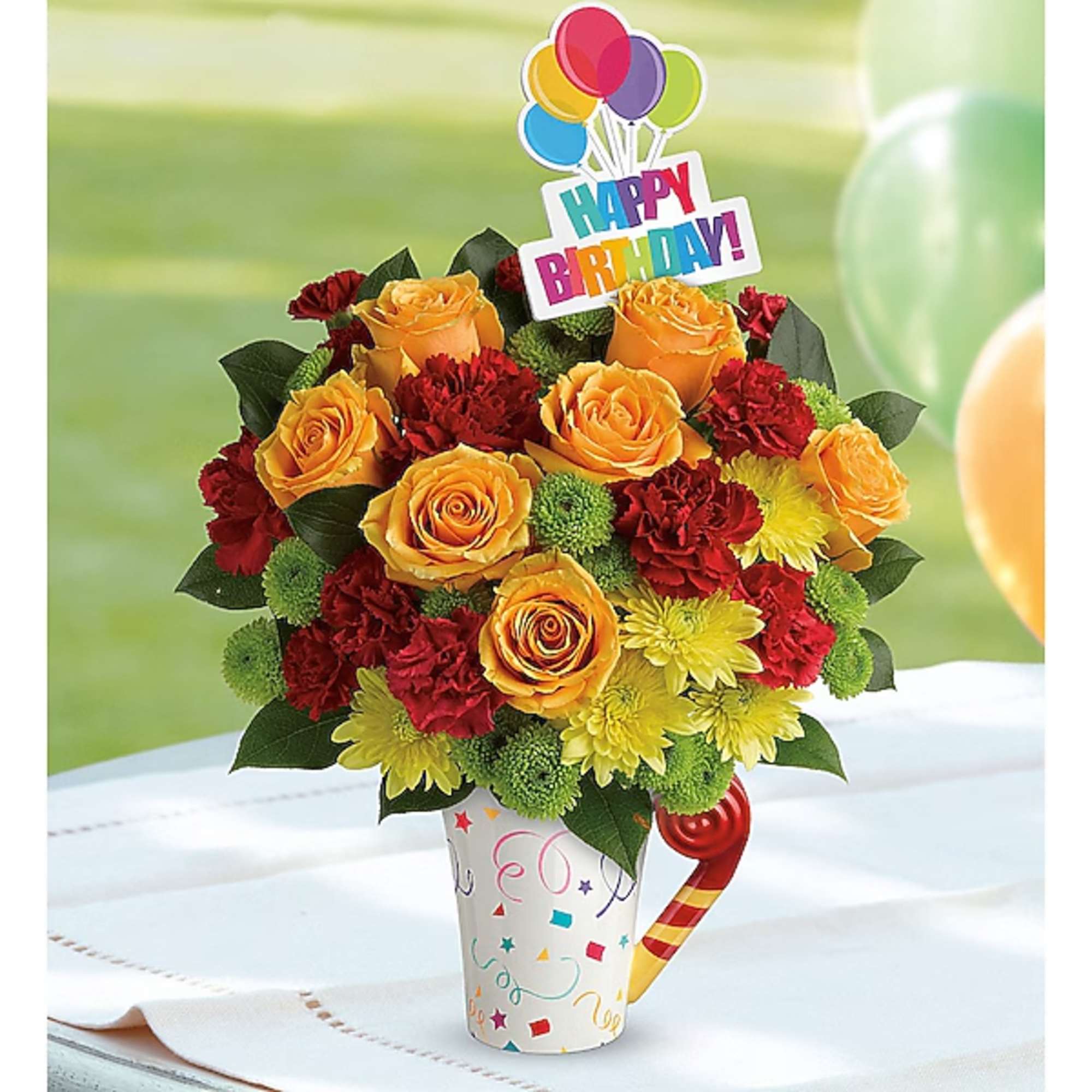 Birthday bouquet of orange roses, red carnations, and yellow mums in a party cup