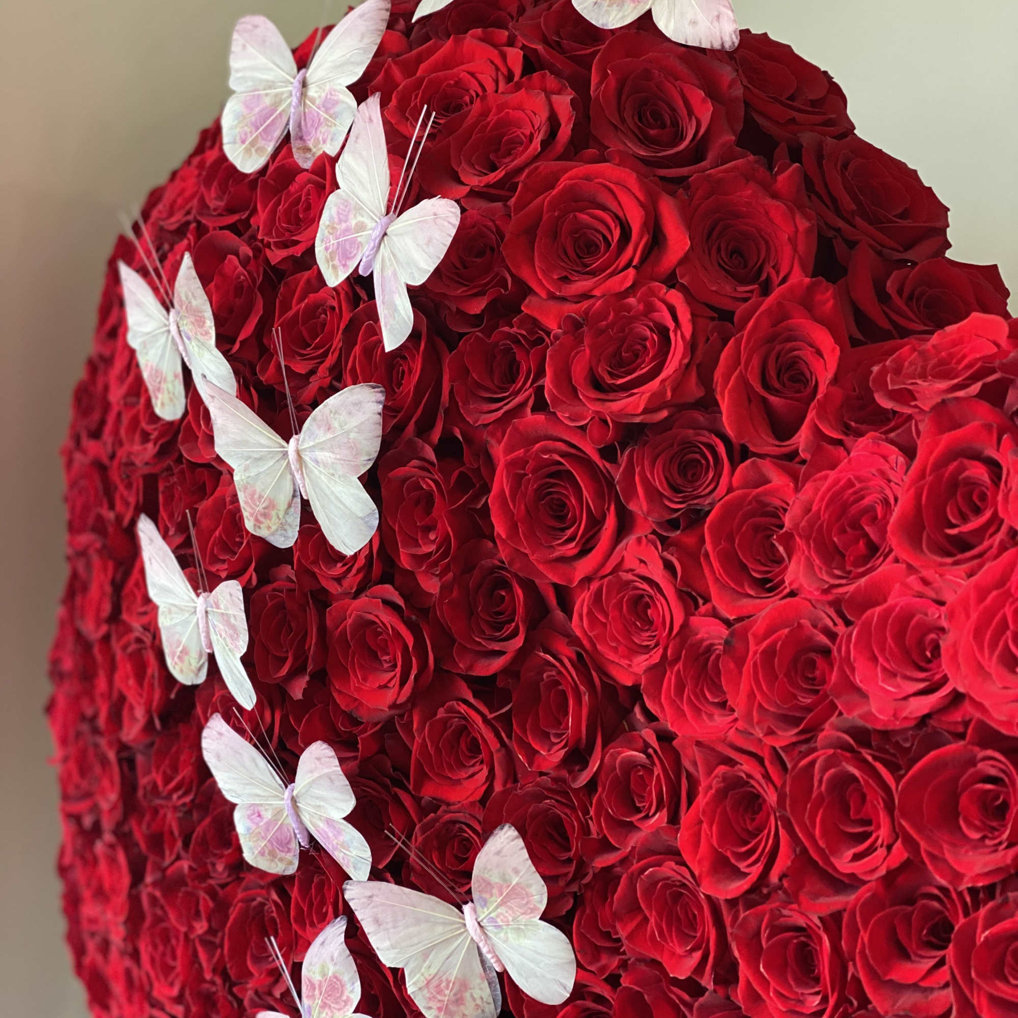 Dense red rose arrangement with pale butterfly decorations