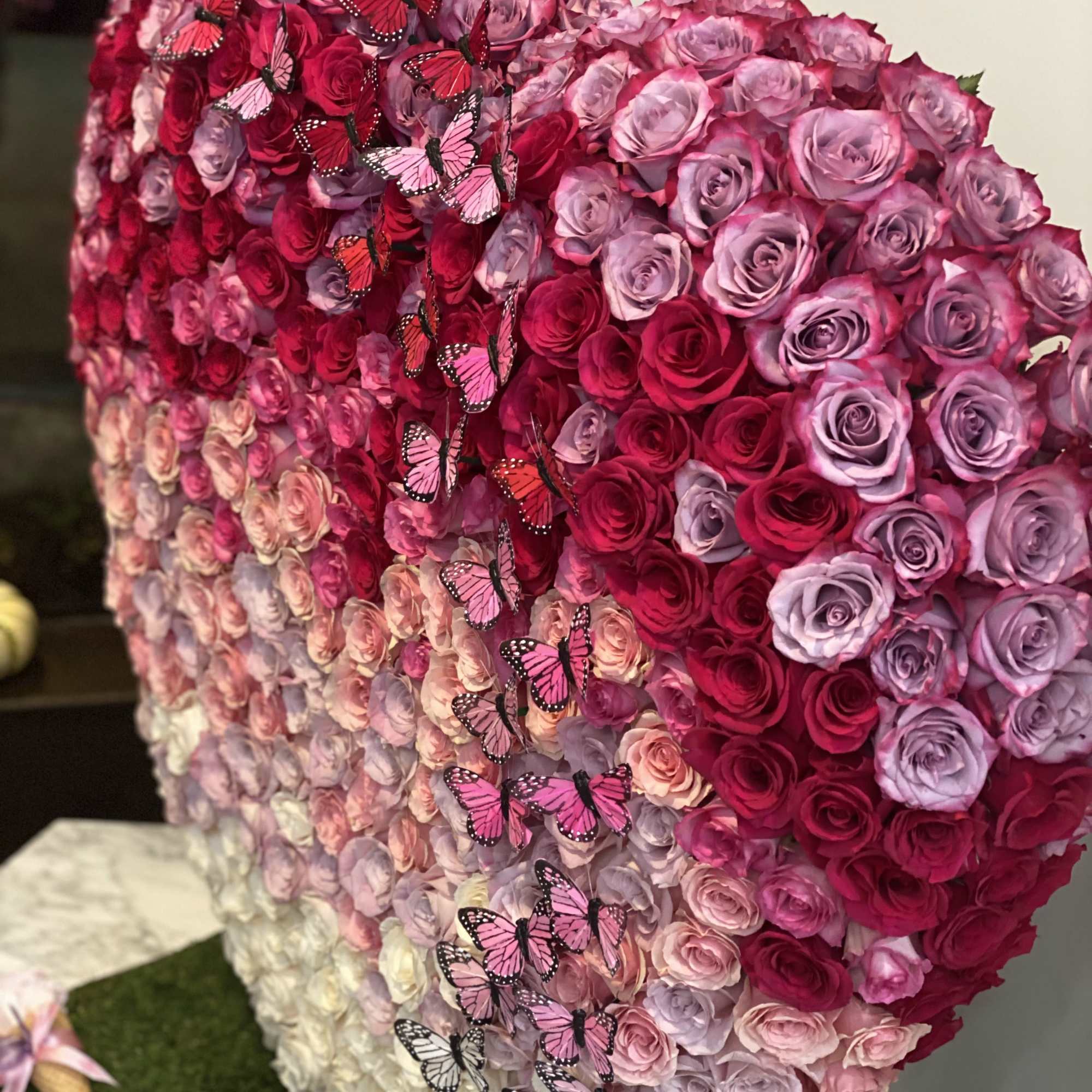 Heart-shaped rose arrangement with pink and red butterflies