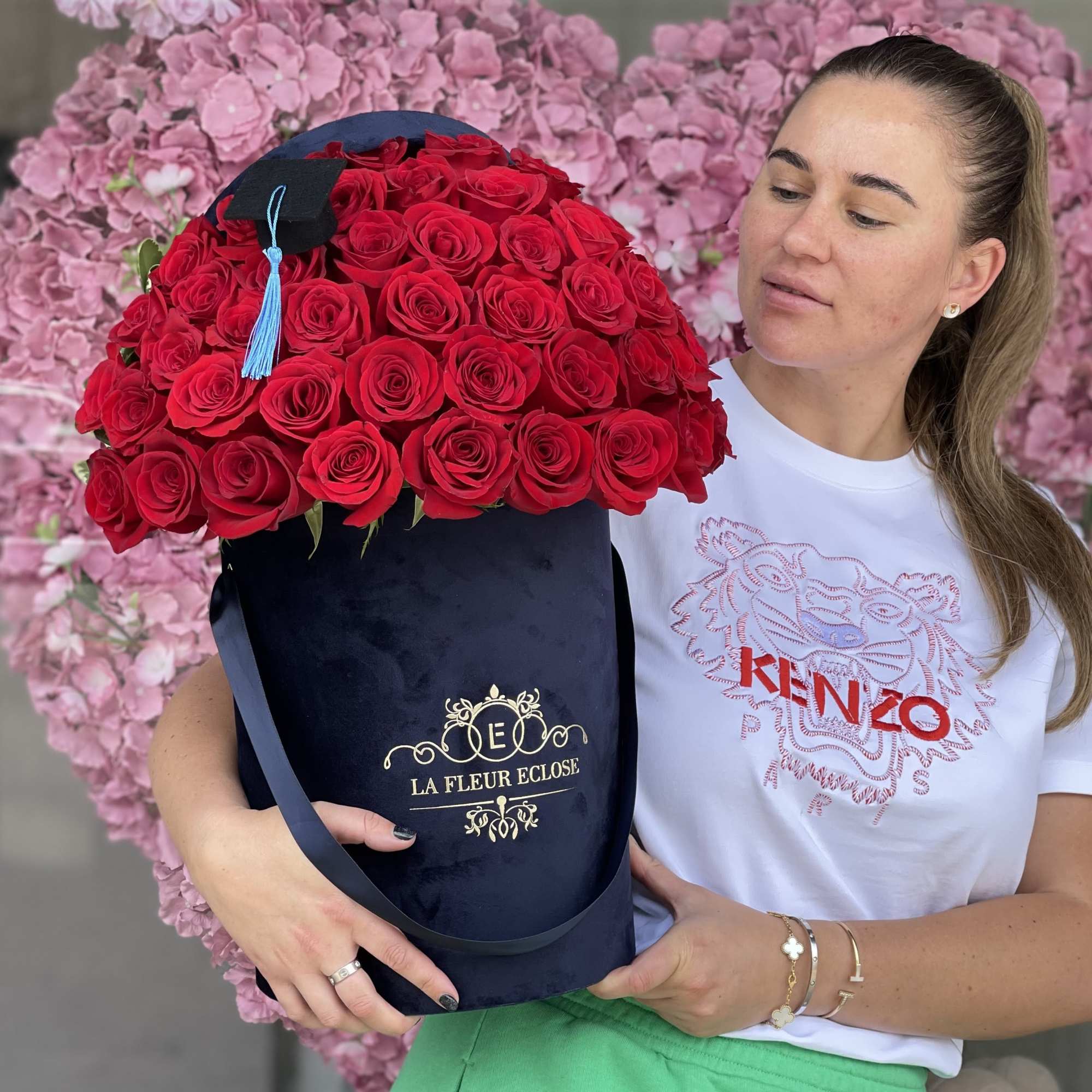 Large bouquet of red roses in a navy hat box with a graduation cap topper