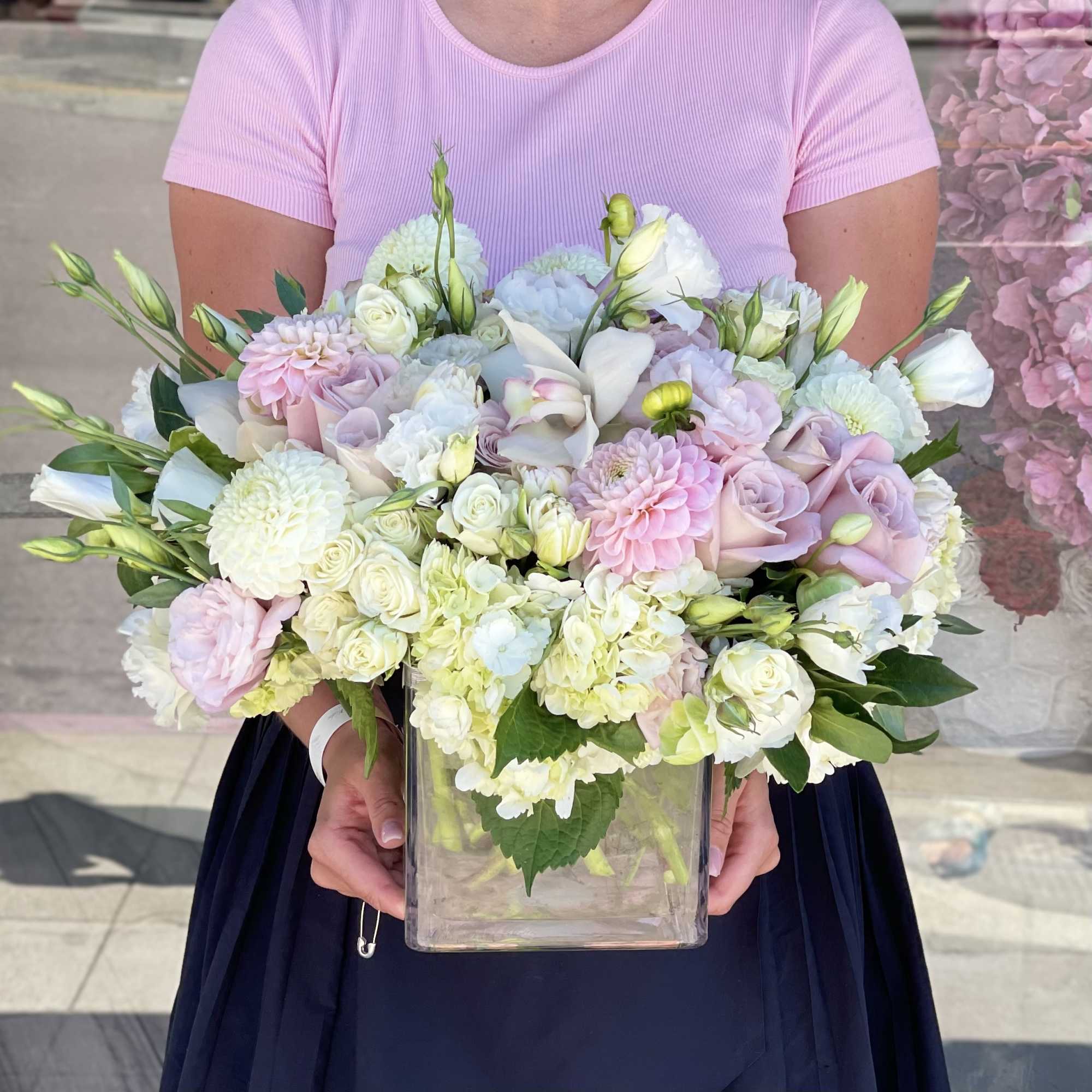 Pastel bouquet of roses, dahlias, and orchids in a clear square vase