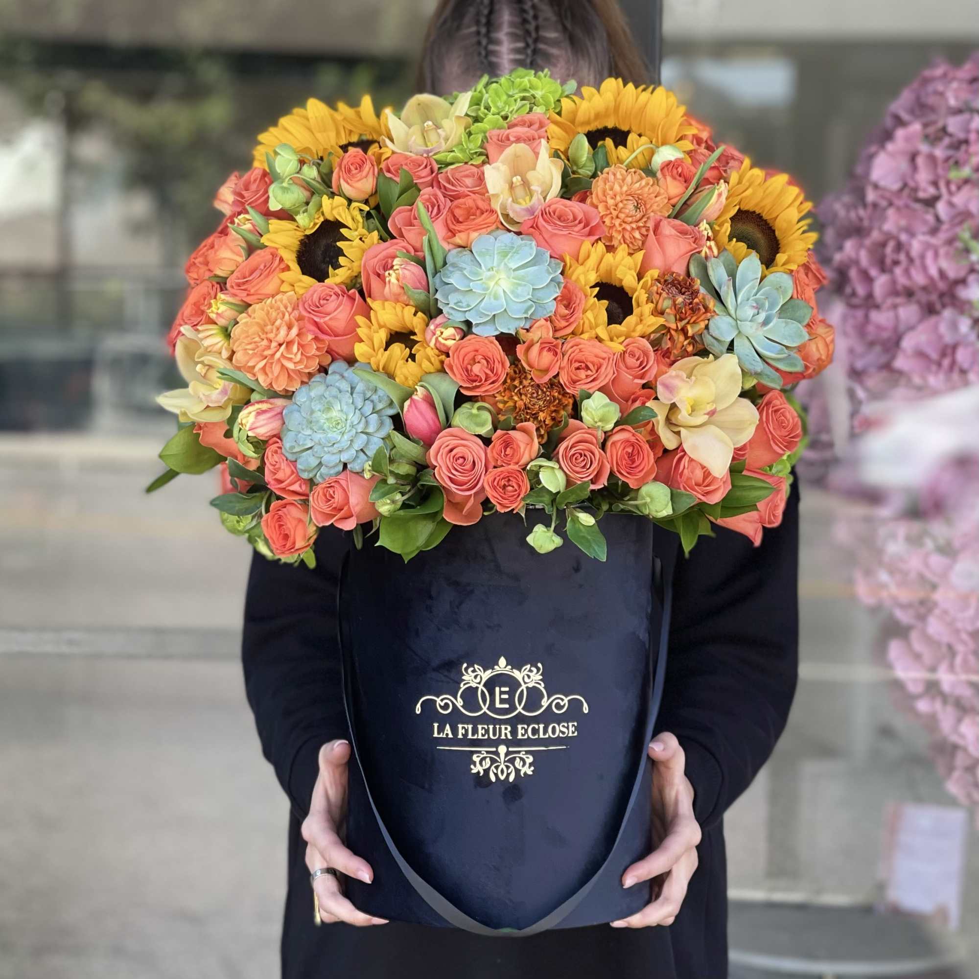 Large bouquet of coral roses and sunflowers in a black box