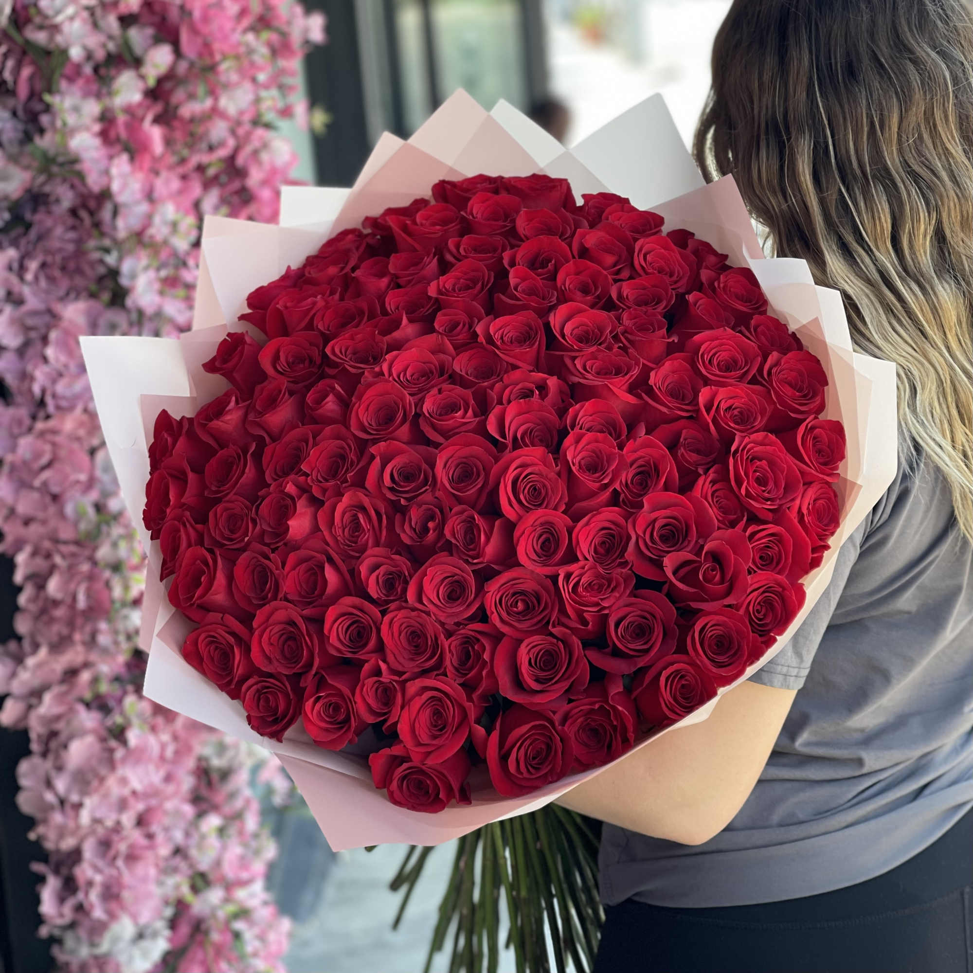 Large bouquet of red roses wrapped in pale pink paper