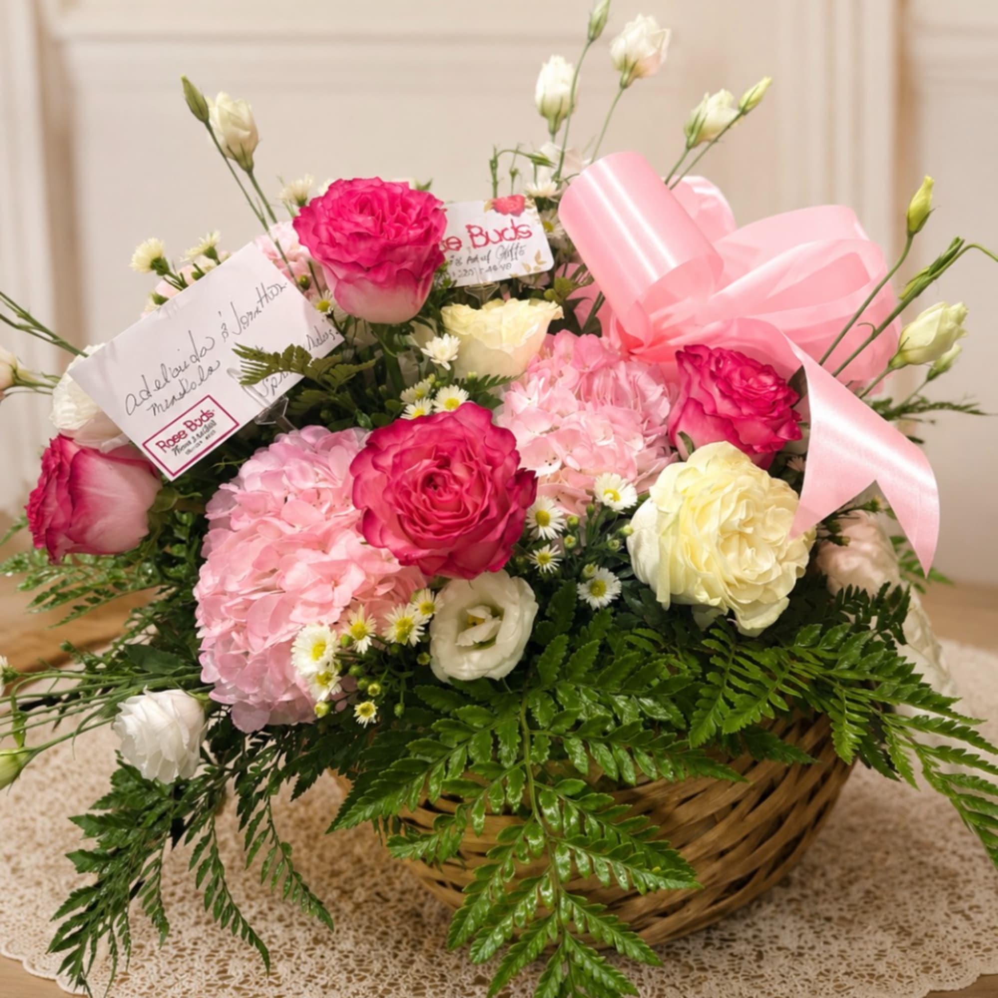 Basket arrangement of pink and white flowers with a pink ribbon.