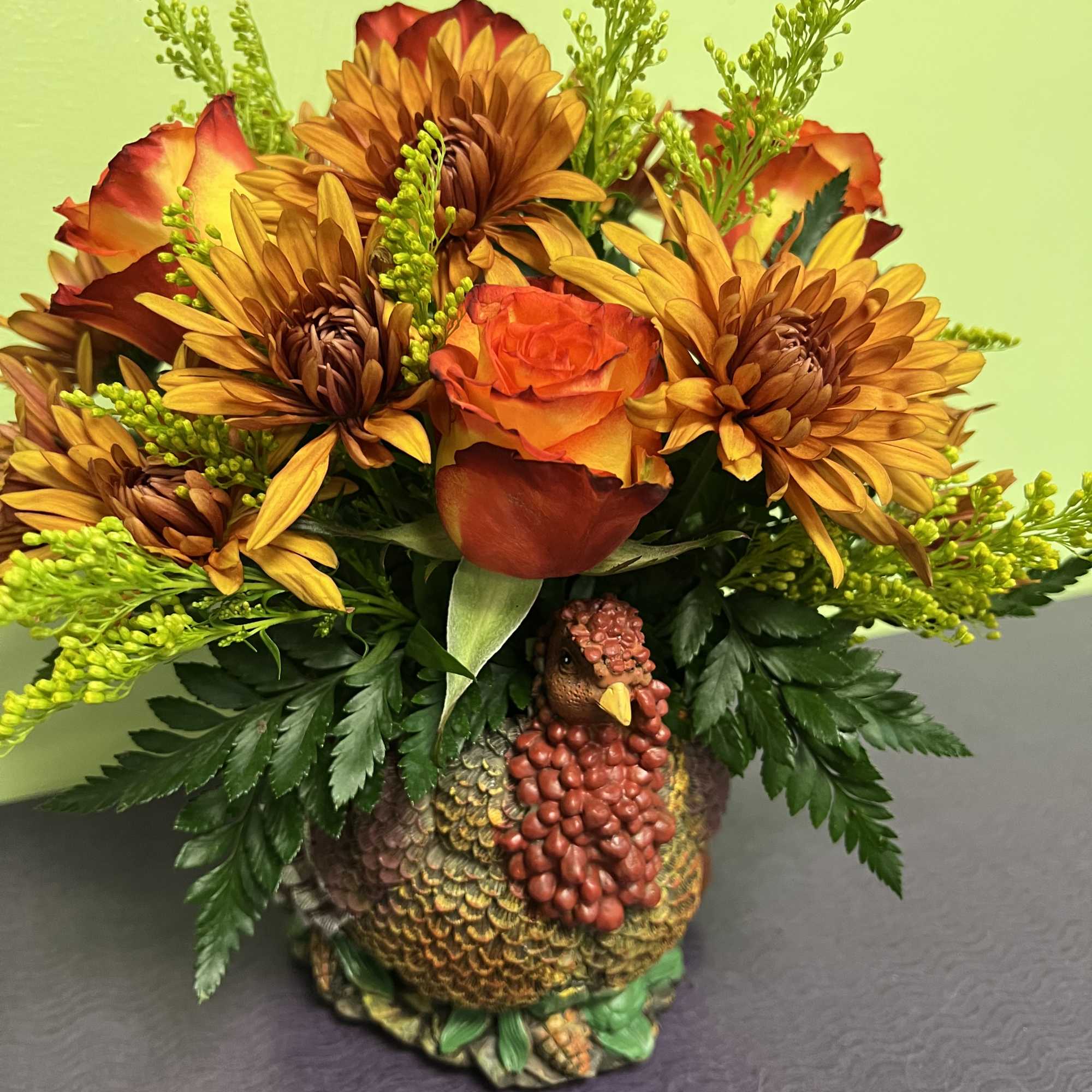 Autumn bouquet with orange roses and yellow chrysanthemums in a turkey-shaped vase