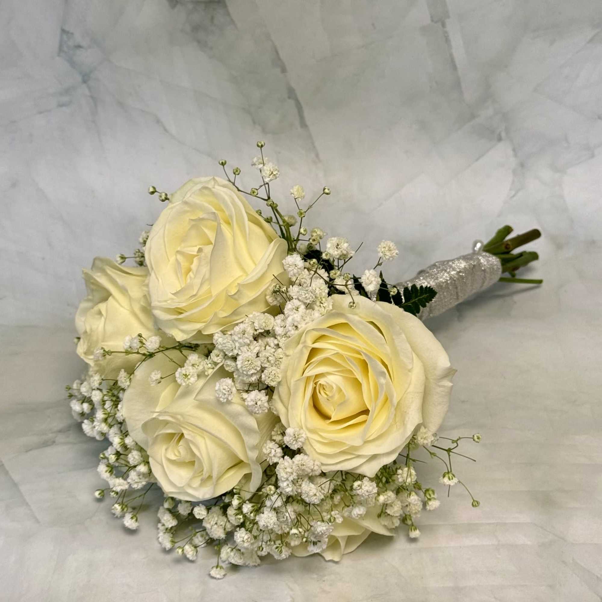 White roses gathered into a compact, rounded hand-tied bouquet create an immediate