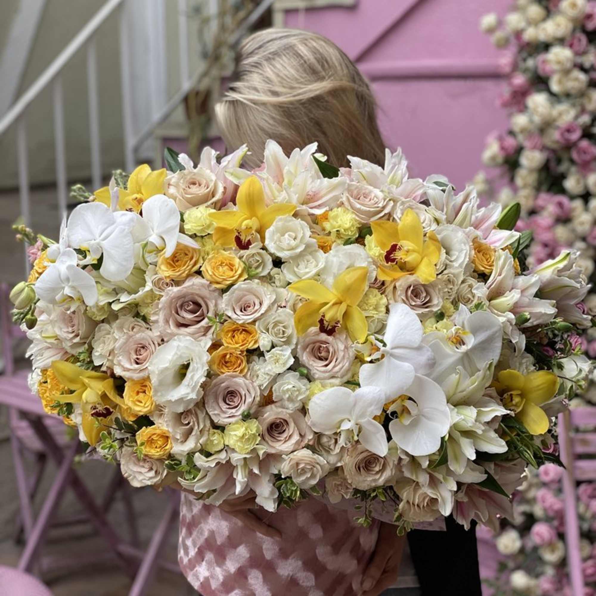 Large bouquet of white, cream, and yellow flowers held by a person