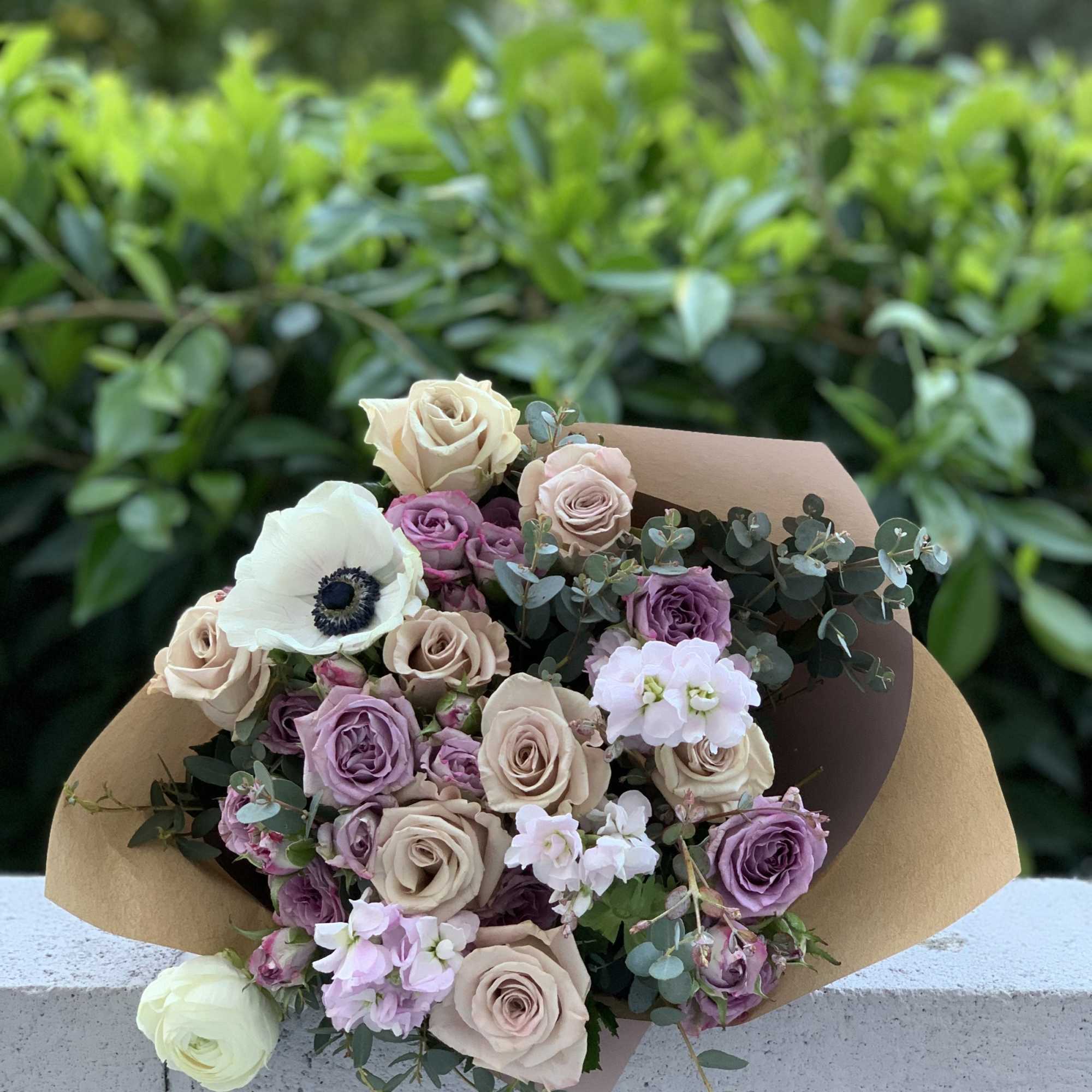 Bouquet of beige, lavender, and white roses with paper wrap